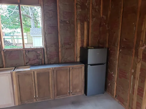 Partially finished kitchen area with exposed insulation and wooden cabinetry.