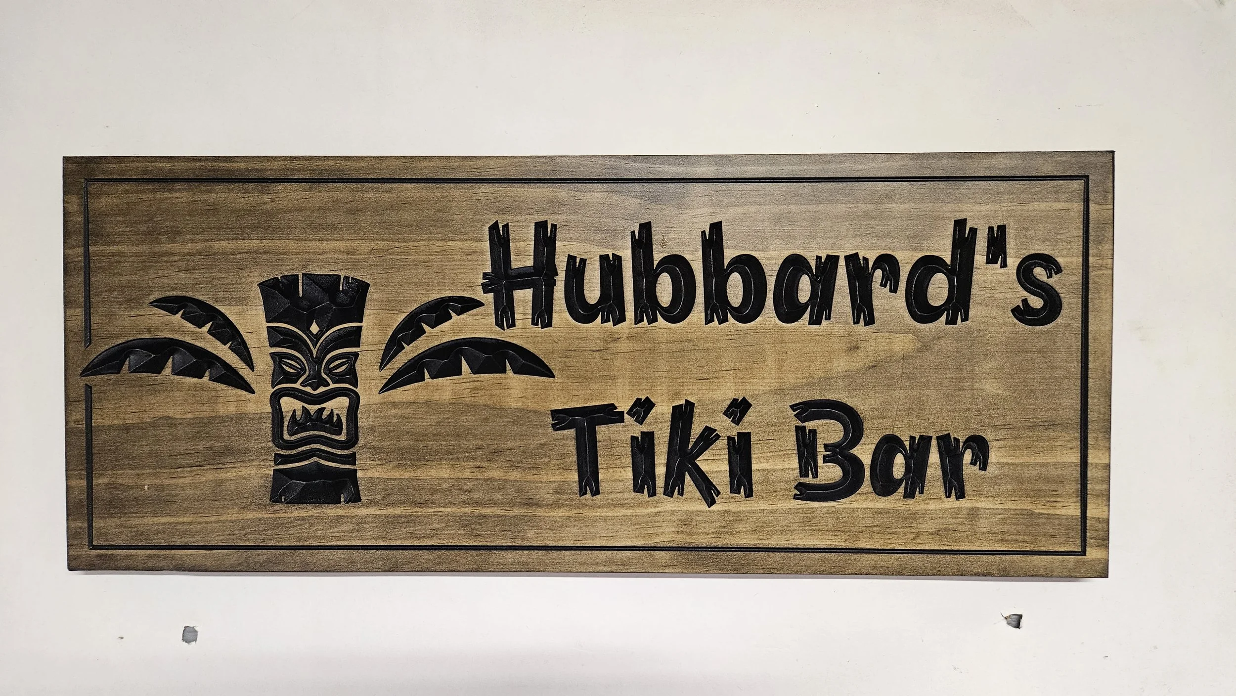 Close-up detail of hand carved wooden Tiki mask with intricate headdress and facial features on custom Tiki Bar sign