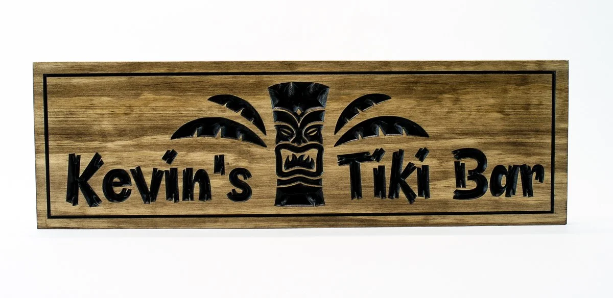 Full view of hand carved wooden Tiki Bar sign with Tiki mask and palm fronds mounted on wall - custom tropical home bar decor