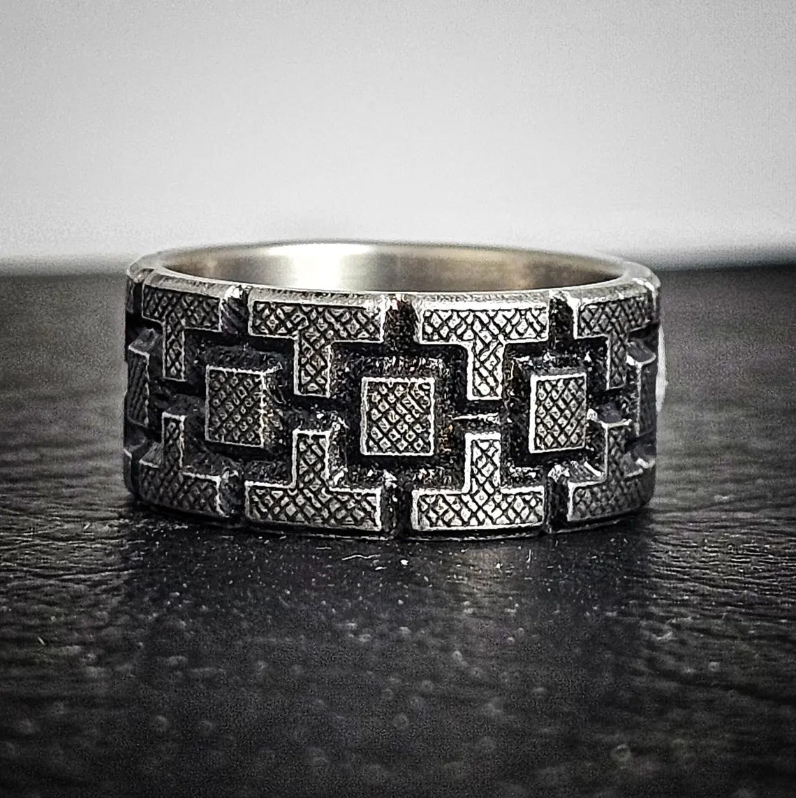 Angled view of Battleworn Titanium Wedding Ring – Rook Design, showing the 10mm width, inner comfort fit, and maker's mark on polished titanium interior