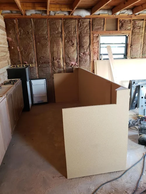 Exposed insulated wall studs, a window and cabinetry during renovation.
