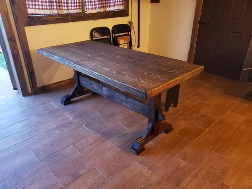 Rustic wooden table by a window with checkered curtains.