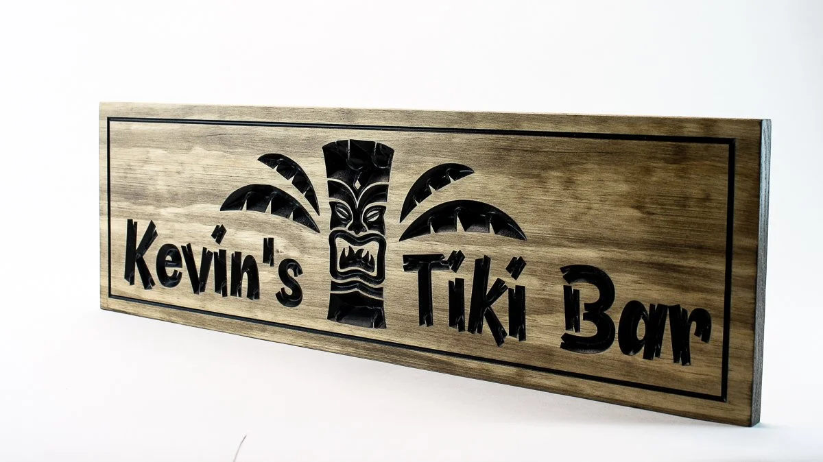 Angled view of hand carved wooden Tiki Bar sign showing depth and 3D carving with palm fronds and personalized text