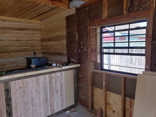 Wooden walls with a new window and exposed insulation.