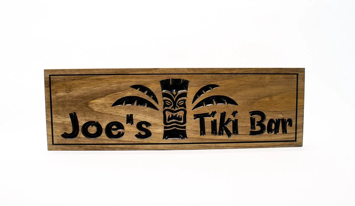 Full view of hand carved wooden Tiki Bar sign with Tiki mask and palm fronds mounted on wall - custom tropical home bar decor