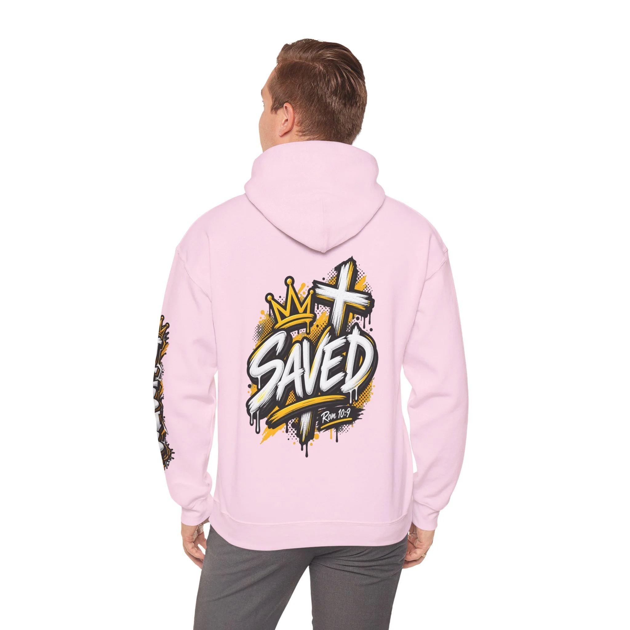 Light pink Unisex streetwear hoodie featuring bold graffiti-style 'SAVED' lettering, a crown, a cross, halftone patterns, and 'Rom 10:9'.