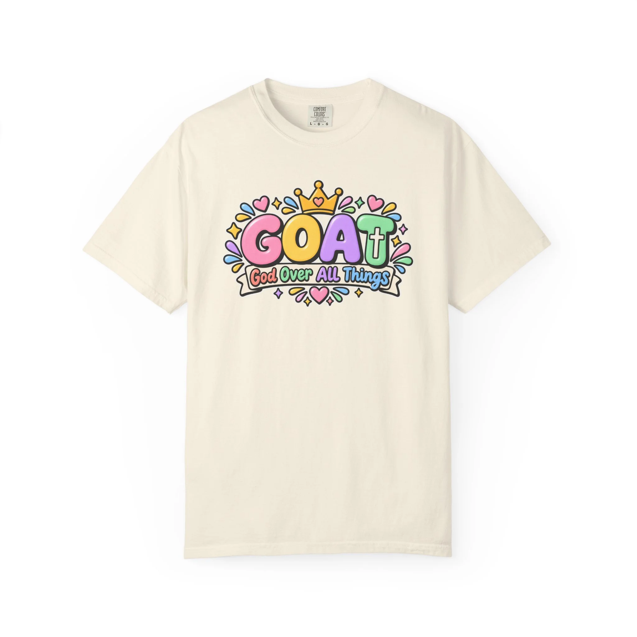 Sand unisex t-shirt graphic showing cute 3D pastel bubble letters spelling GOAT, a yellow crown with a heart, hearts, sparkles, and a banner below that reads "God Over All Things".