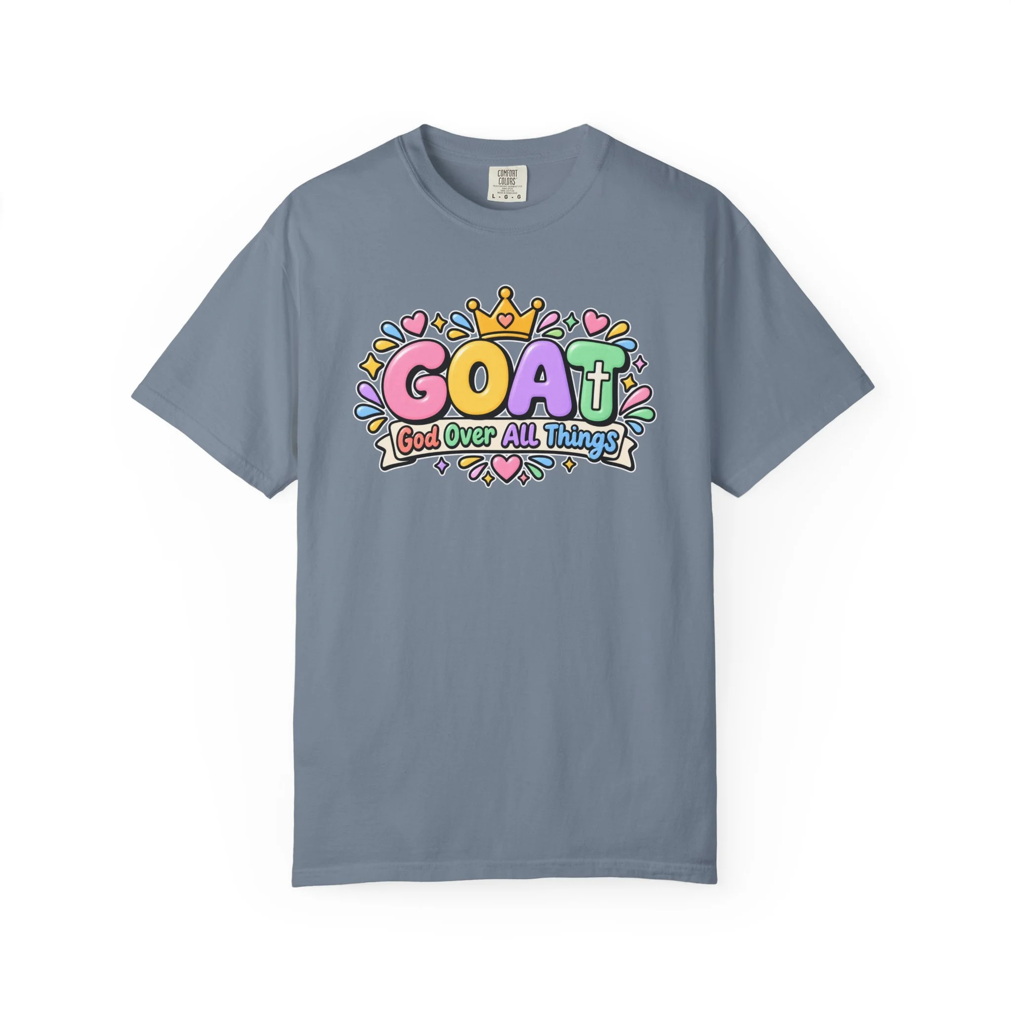 Denim blue unisex t-shirt graphic showing cute 3D pastel bubble letters spelling GOAT, a yellow crown with a heart, hearts, sparkles, and a banner below that reads "God Over All Things".