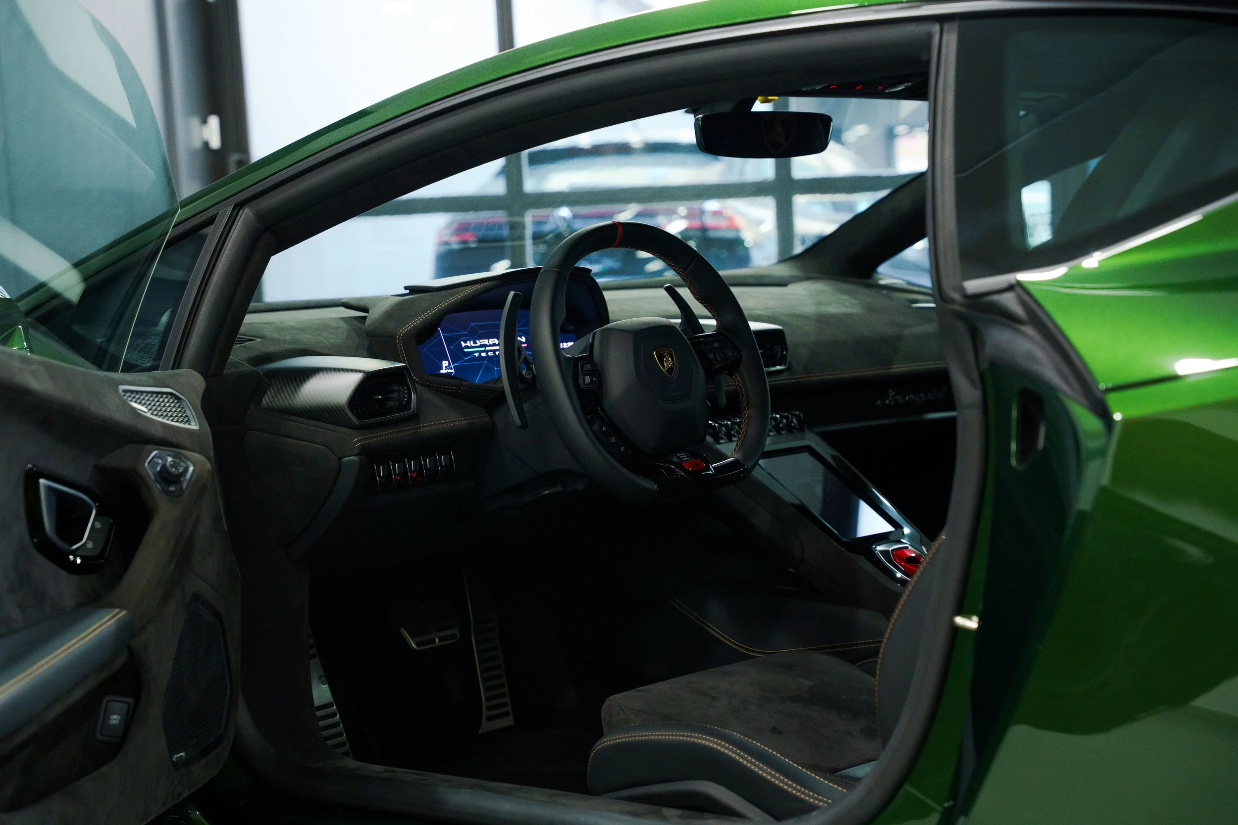 Interior of a green Lamborghini sports car, showing the dashboard, steering wheel, and driver's seat with black and yellow detailing.