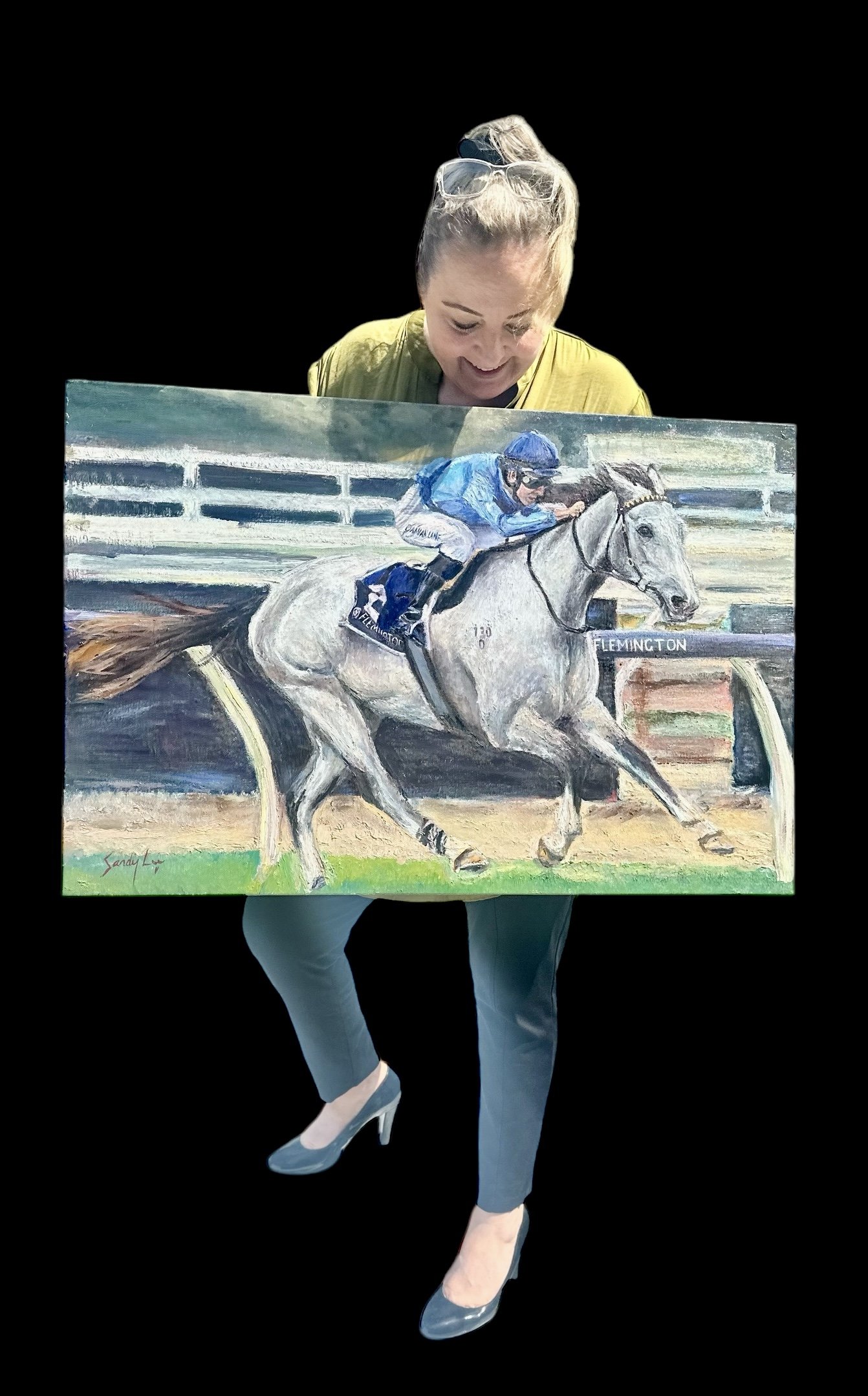 Woman holding a realistic painting of a horse race, showing a jockey riding a grey horse near a racetrack with a sign reading 'Flemington'.