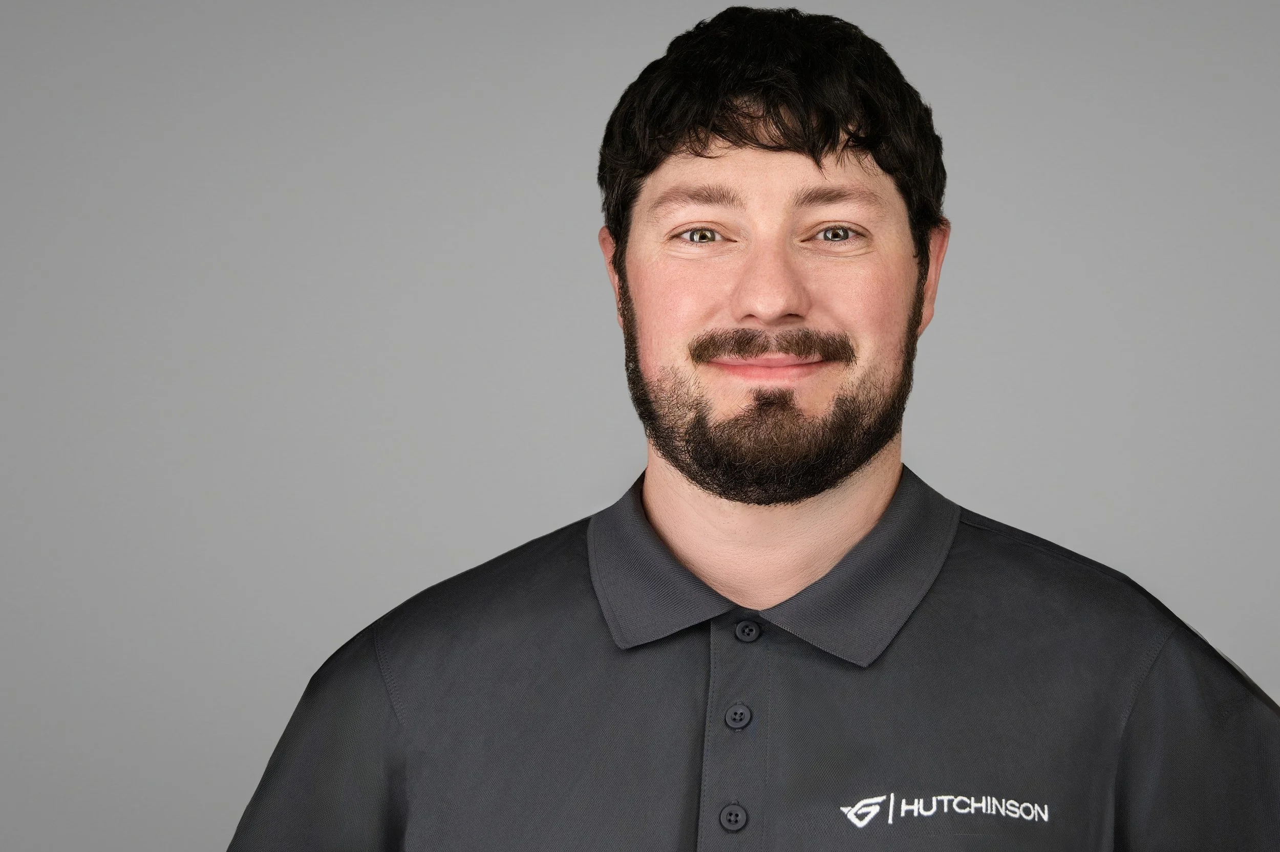l headshot of a manufacturing and automotive supplier employee wearing a dark gray Hutchinson polo against a light gray background.