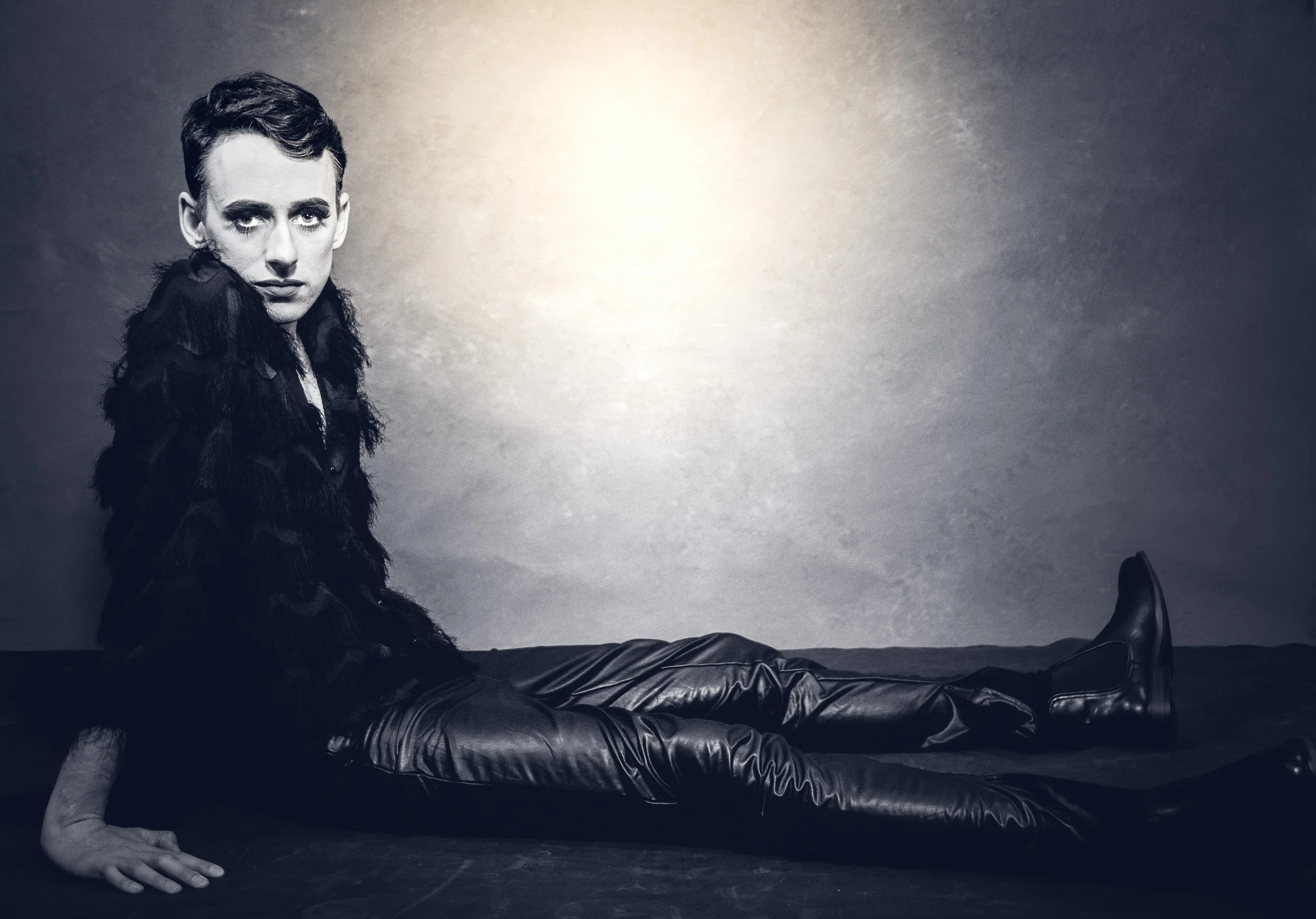 Yevette Lynn, brand photographer, captures a dramatic studio portrait of a woman in dark fashion seated on the floor with a strong, editorial pose.