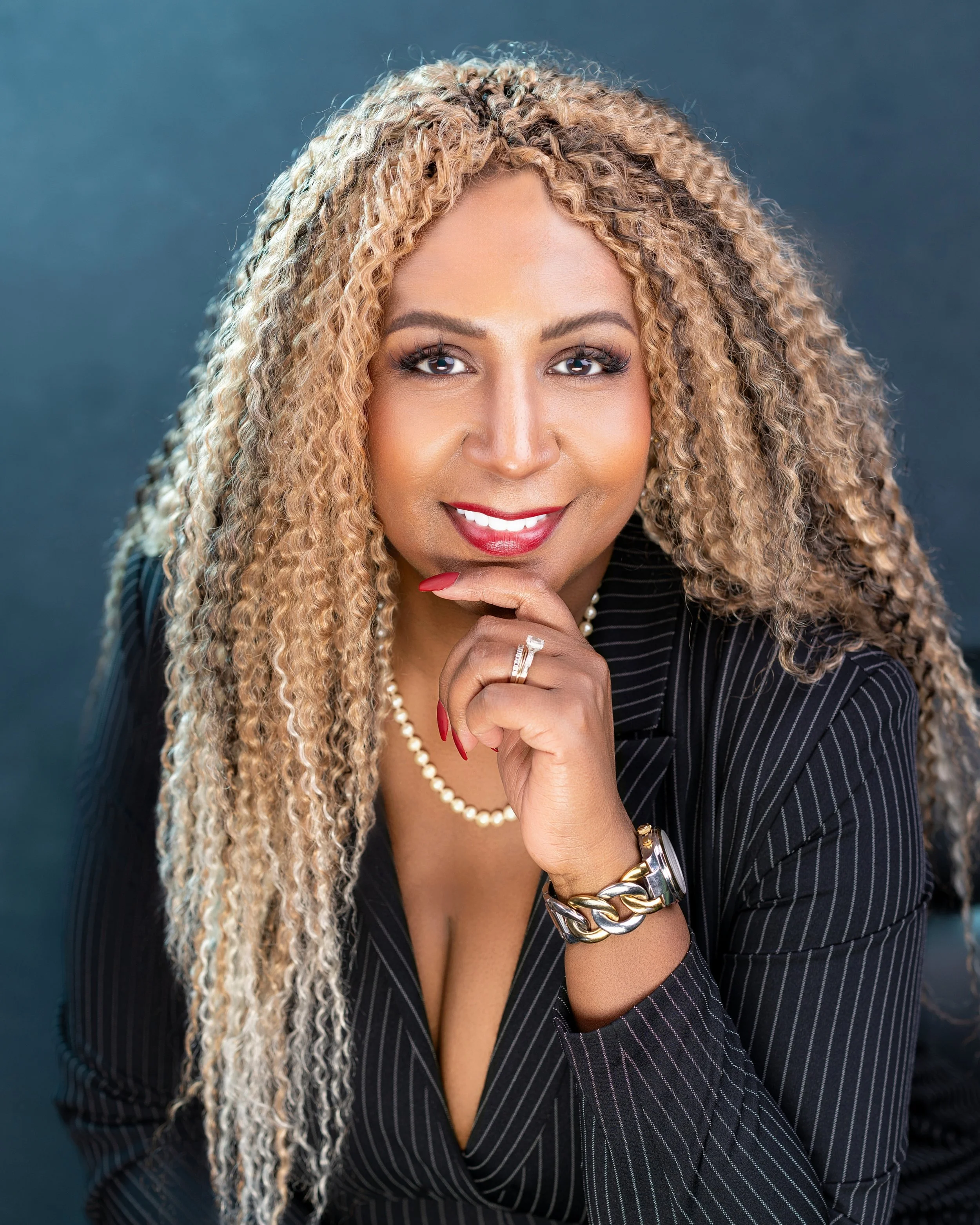 Yevette Lynn headshot photographer captured as confident businesswoman with curly hair smiling, polished studio portrait emphasizing leadership presence and professional personal branding.