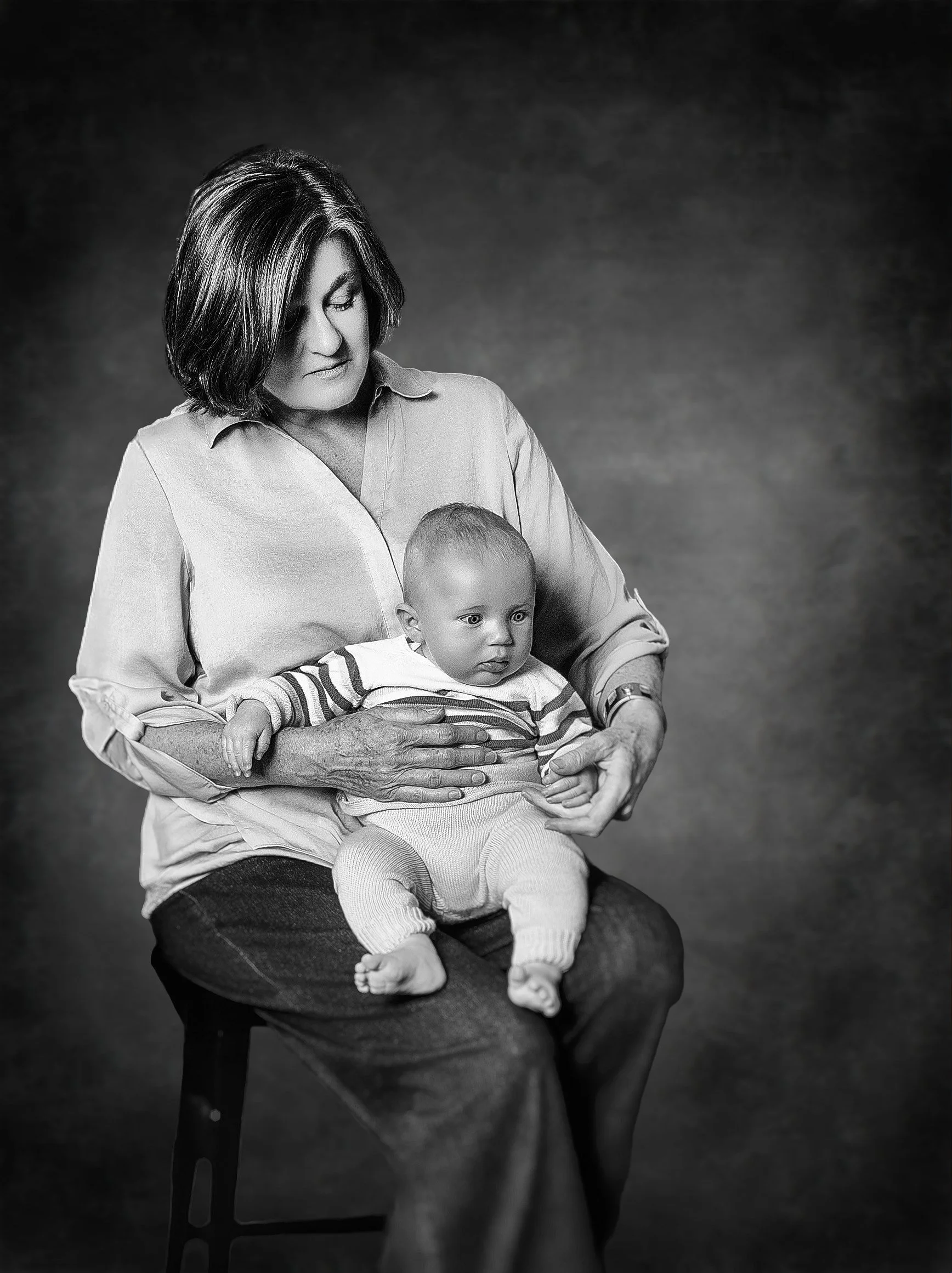 Yevette Lynn portrait photographer captures black and white family portrait of mother holding baby, seated gently against studio backdrop.