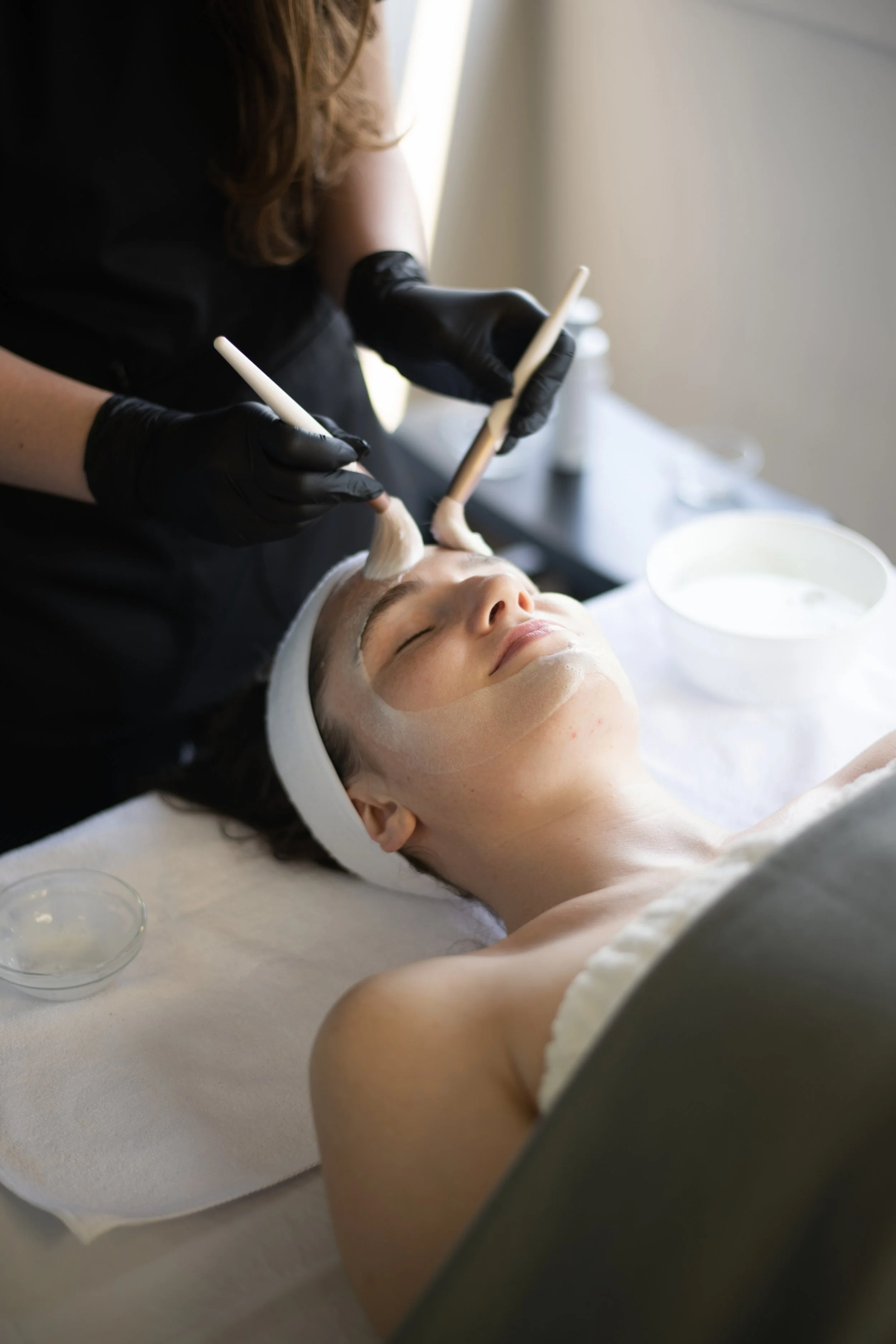 Yevette Lynn, brand photographer, captures a spa brand image of a woman receiving a facial treatment while lying relaxed during a skincare session.