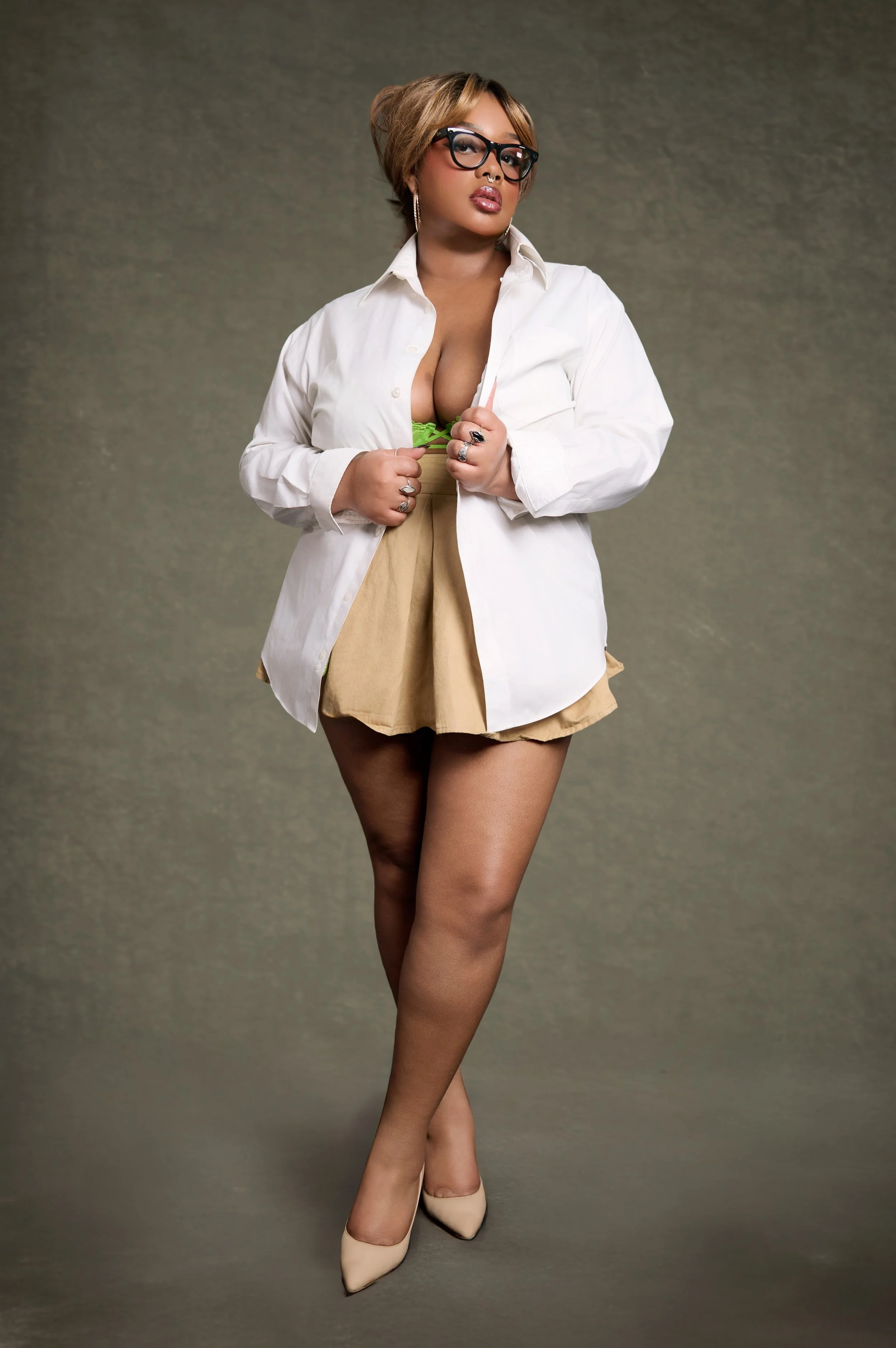 Yevette Lynn portrait photographer captures studio boudoir portrait of woman wearing white button-up shirt and skirt, posed confidently against textured backdrop.