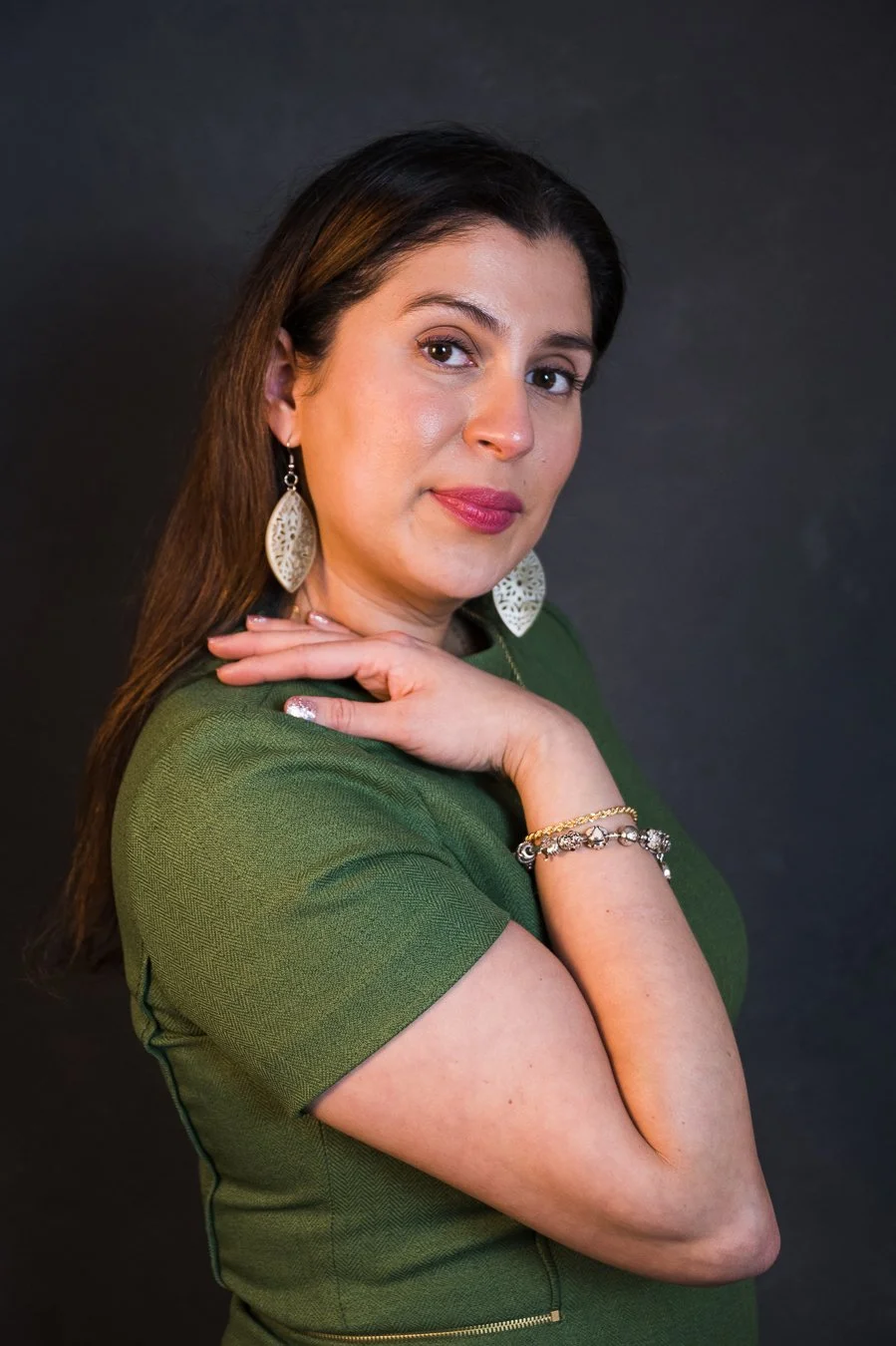 Yevette Lynn portrait photographer creates studio portrait of a woman in green top, posed in profile with hand resting on shoulder.