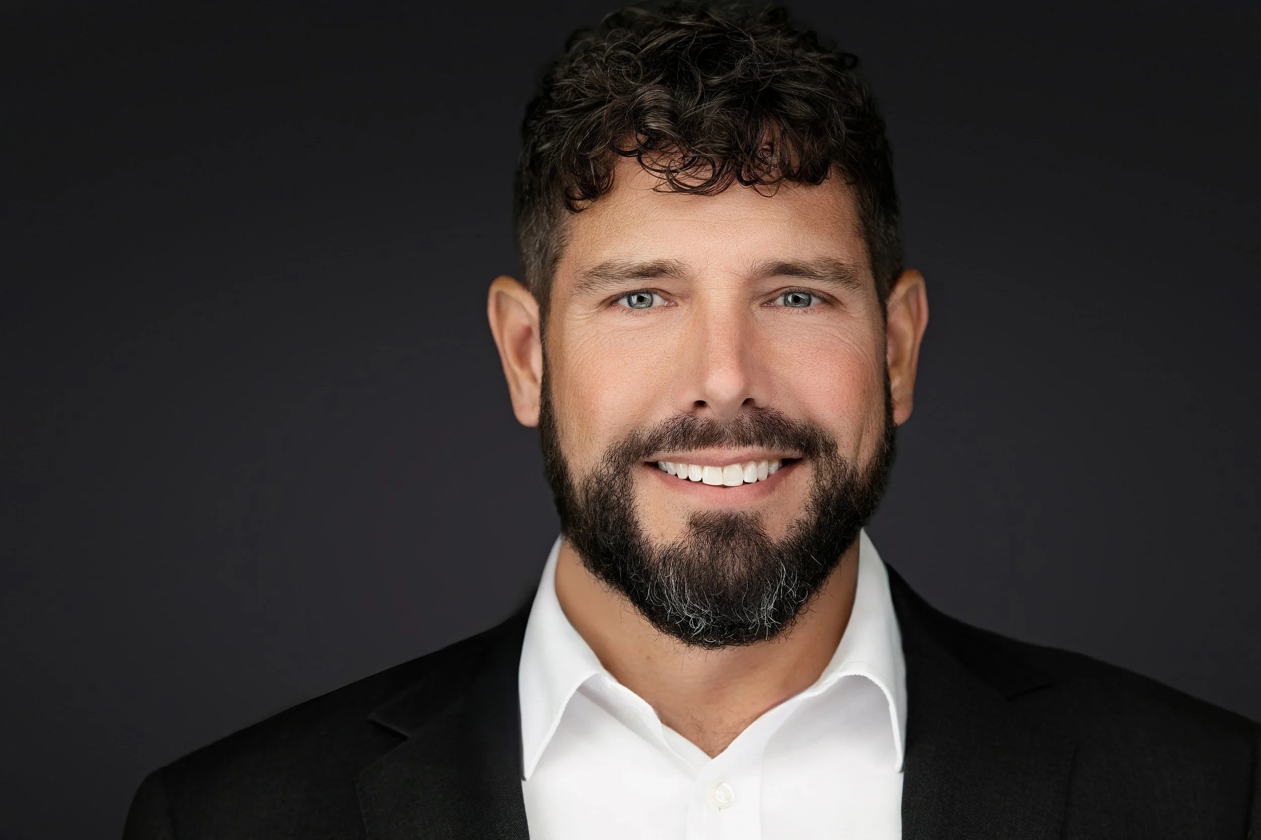 Yevette Lynn, professional photographer, delivers a confident studio headshot portrait for business branding, featuring a bearded man with natural expression and soft lighting.