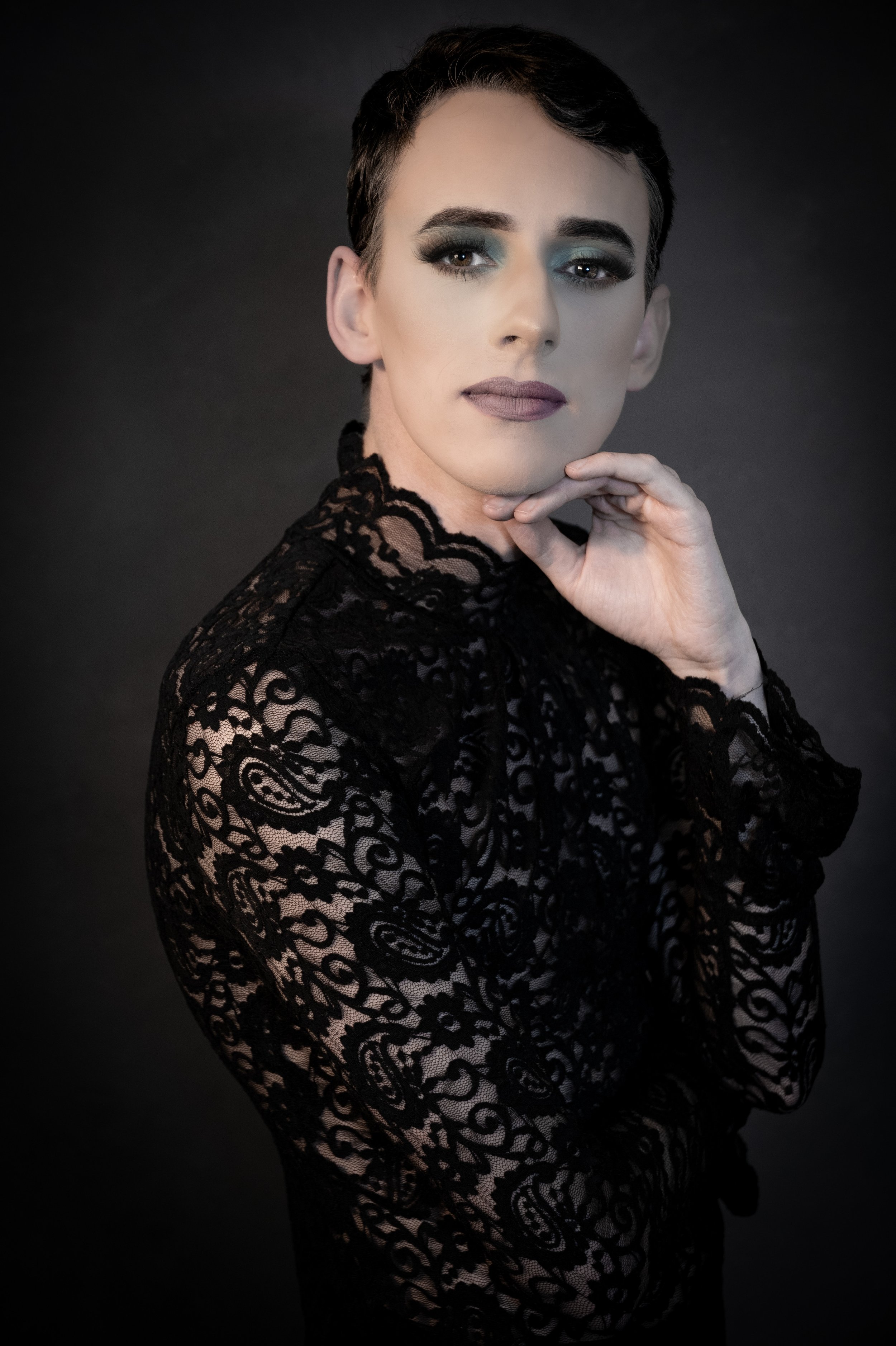 Yevette Lynn, brand photographer, captures a refined studio portrait of a woman in black lace fashion posed elegantly against a dark, moody background.