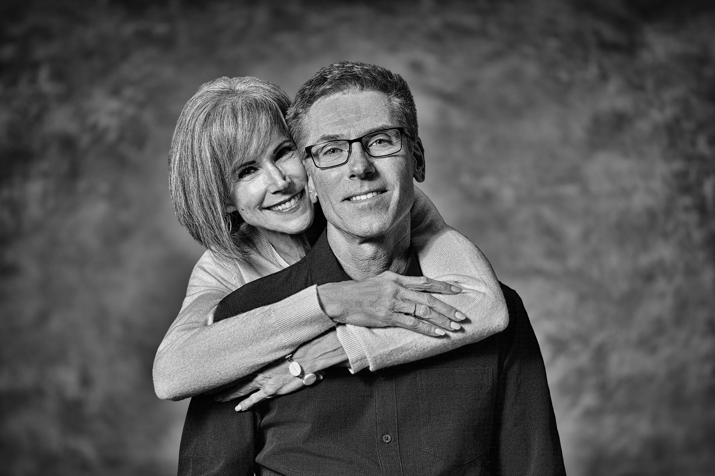 Yevette Lynn portrait photographer capturing a black and white couples portrait of a mature couple sharing a warm, affectionate studio embrace.