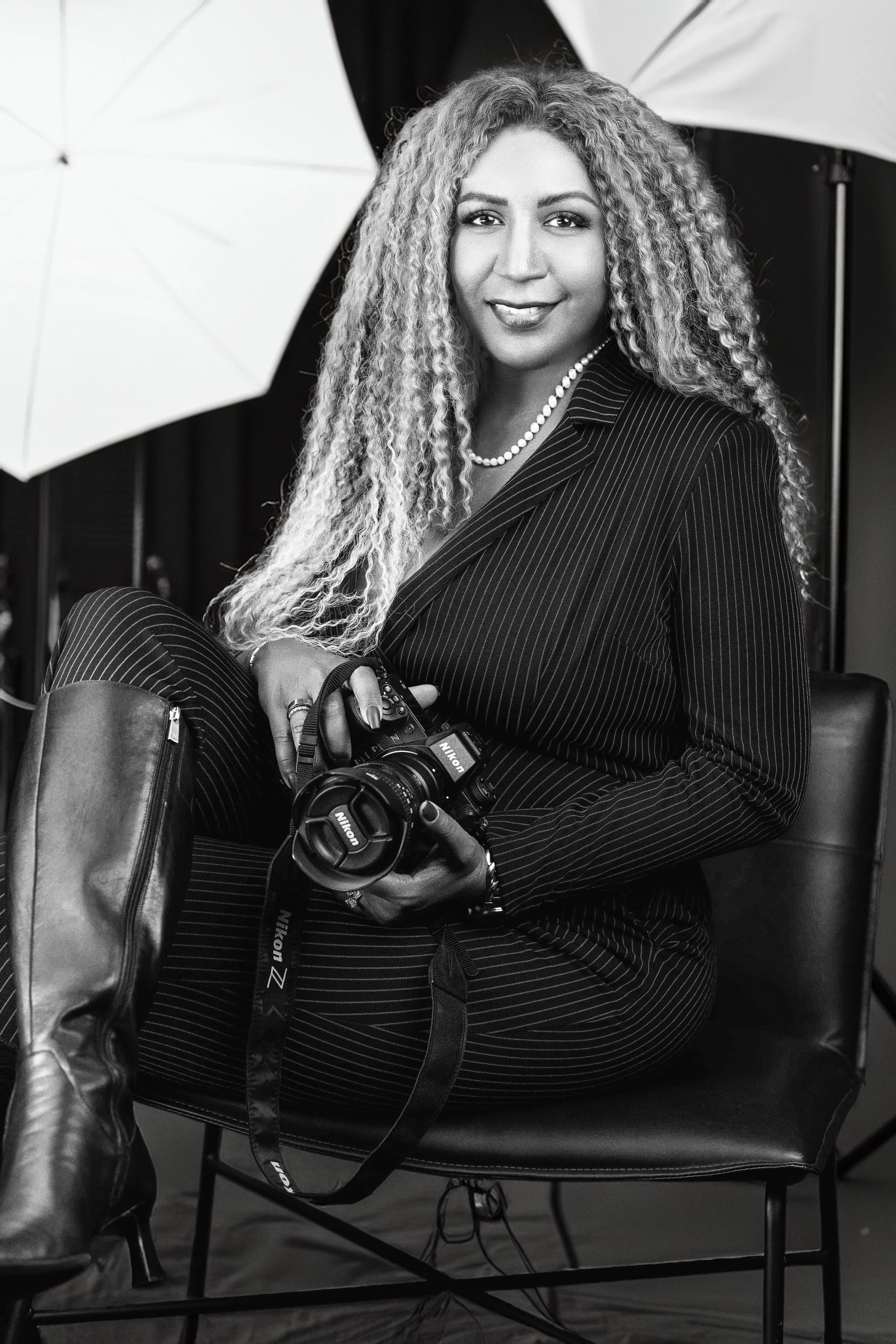 Yevette Lynn, professional photographer, seated in her studio holding a camera during a personal branding portrait session.