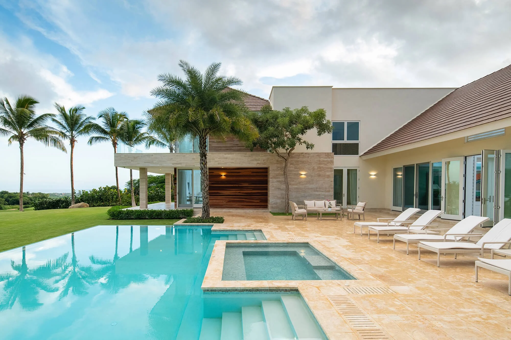 Luxury modern house with a swimming pool, palm trees, and outdoor lounge chairs.