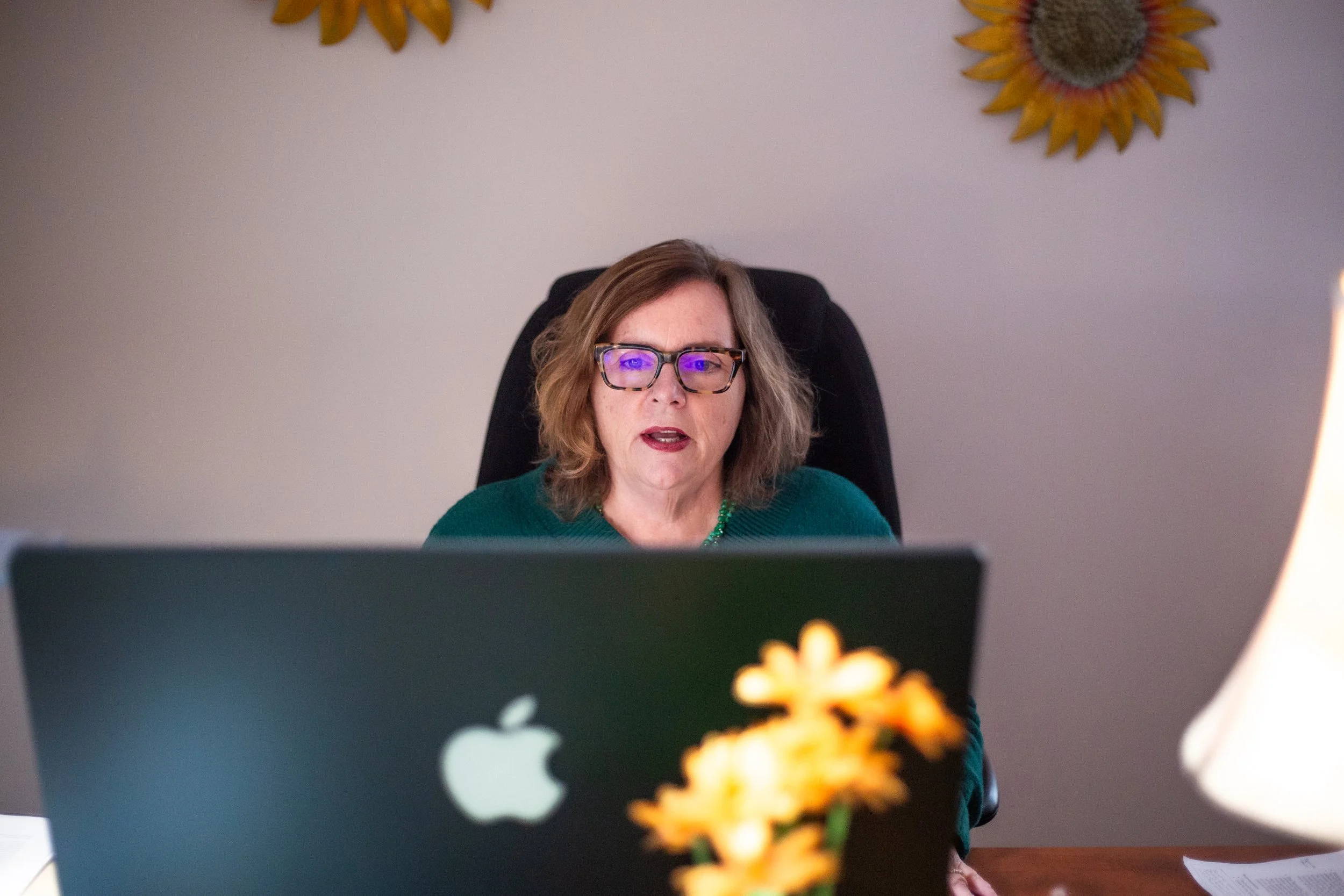 Brunette woman, Betsy, talking to compute on Zoom call with Mac screen