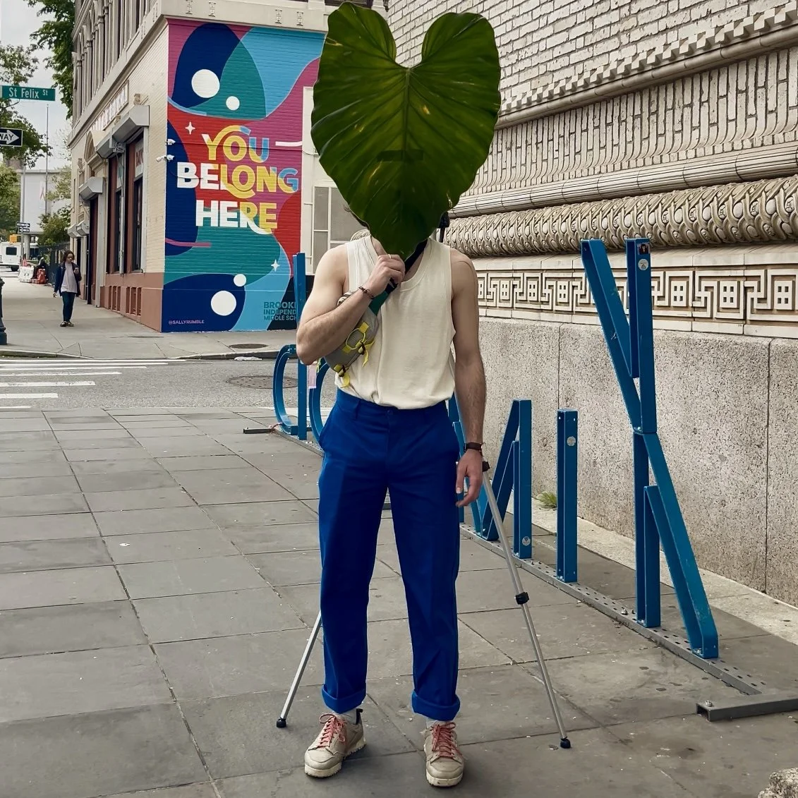 Man standing with a huge leaf in his hand and it is covering her face. Photo taken in New York City as part of the video series LeafHead Field Project.