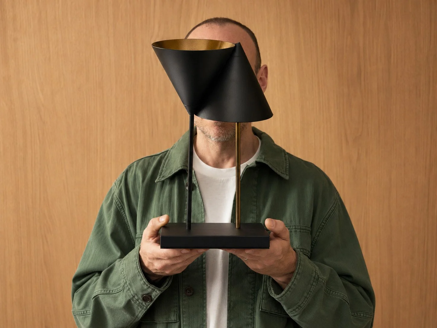 Martin Lenclos holding a desk lamp he designed.