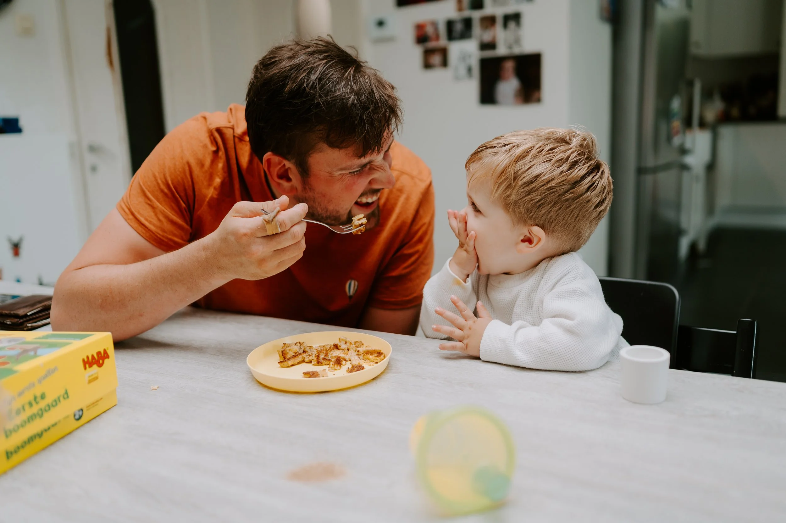 papa eet samen met zoontje aan tafel bij hen thuis tijdens de gezinsshoot
