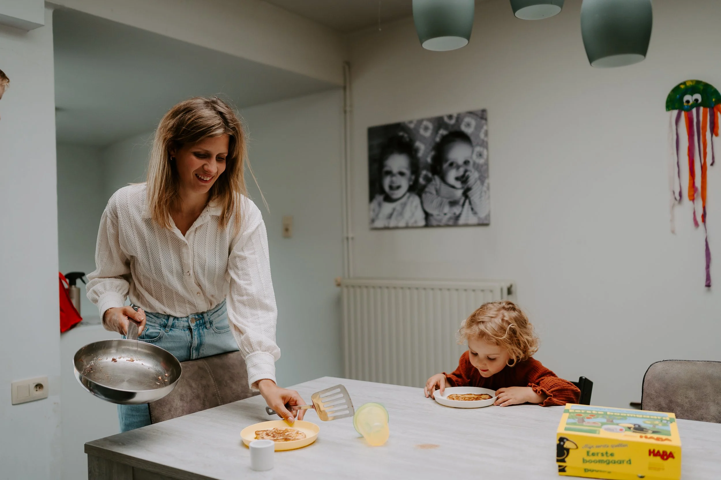 een gezinsfoto waarbij mama eten geeft aan dochter