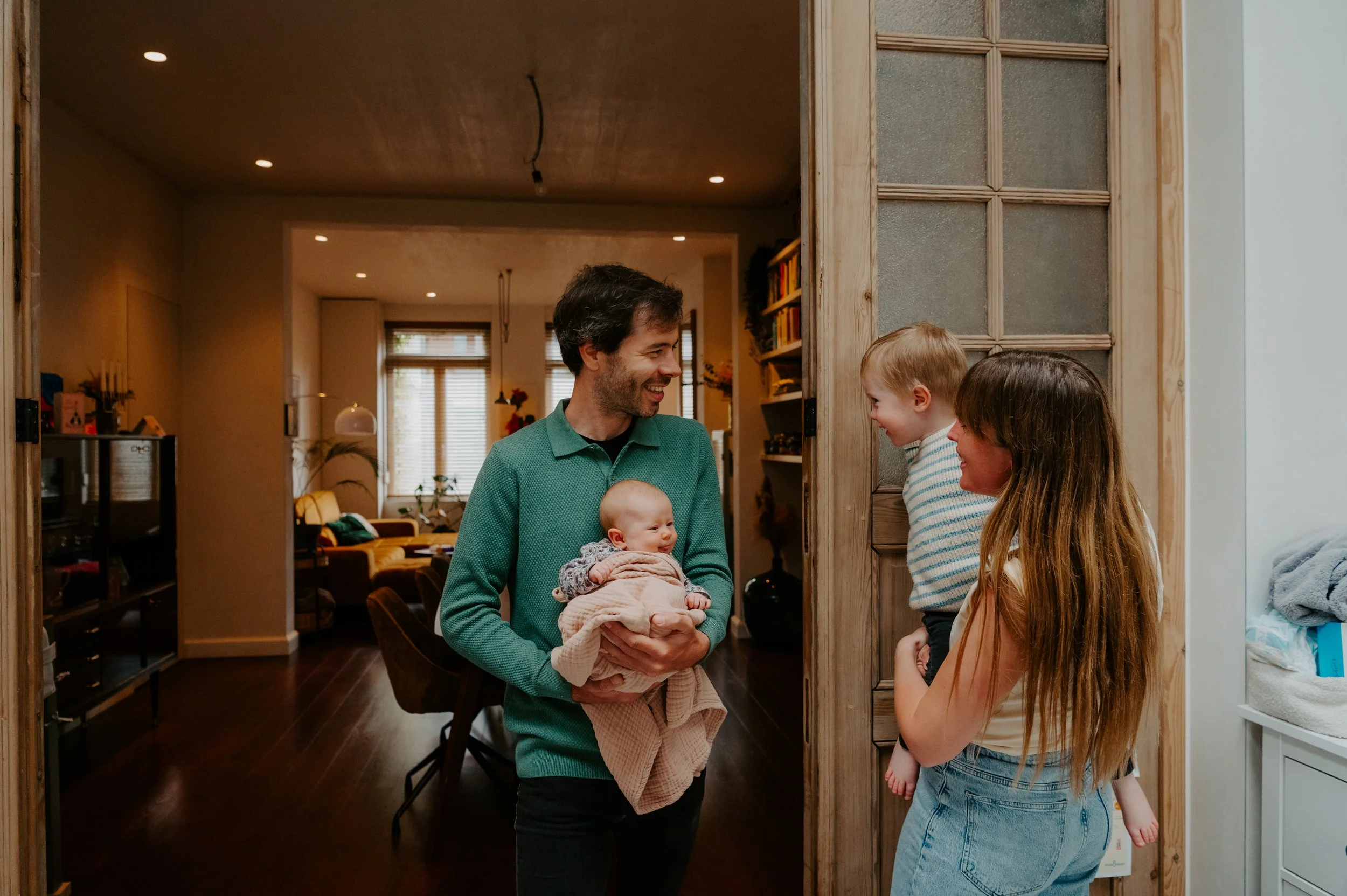 papa brengt de baby naar mama om het badmomentje te geven tijdens een day in the life gezinsreportage