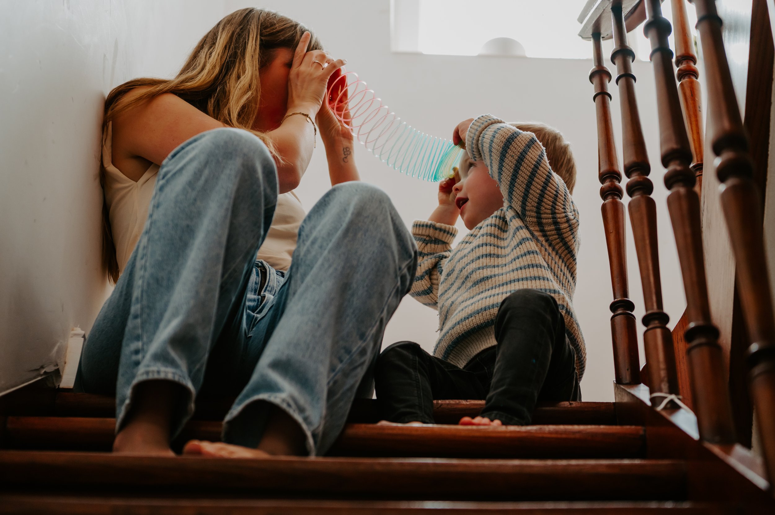 een foto van een mama die speelt met haar zoontje thuis op de trap