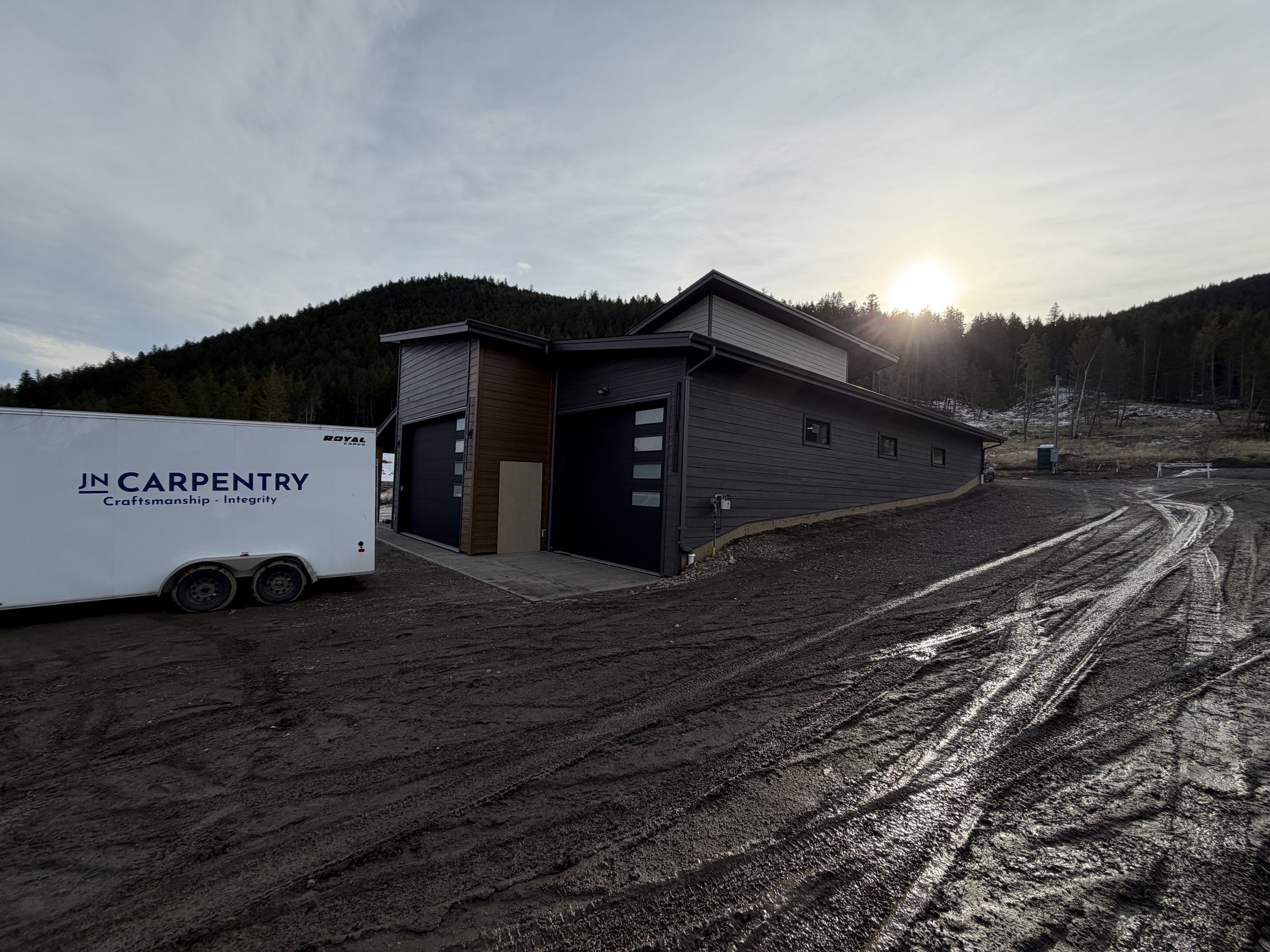 A modern gray house with black accents in a mountainous area with trees on the hillside. Professional siding installation, replacement, and exterior renovations in Williams Lake and the Cariboo Region. 