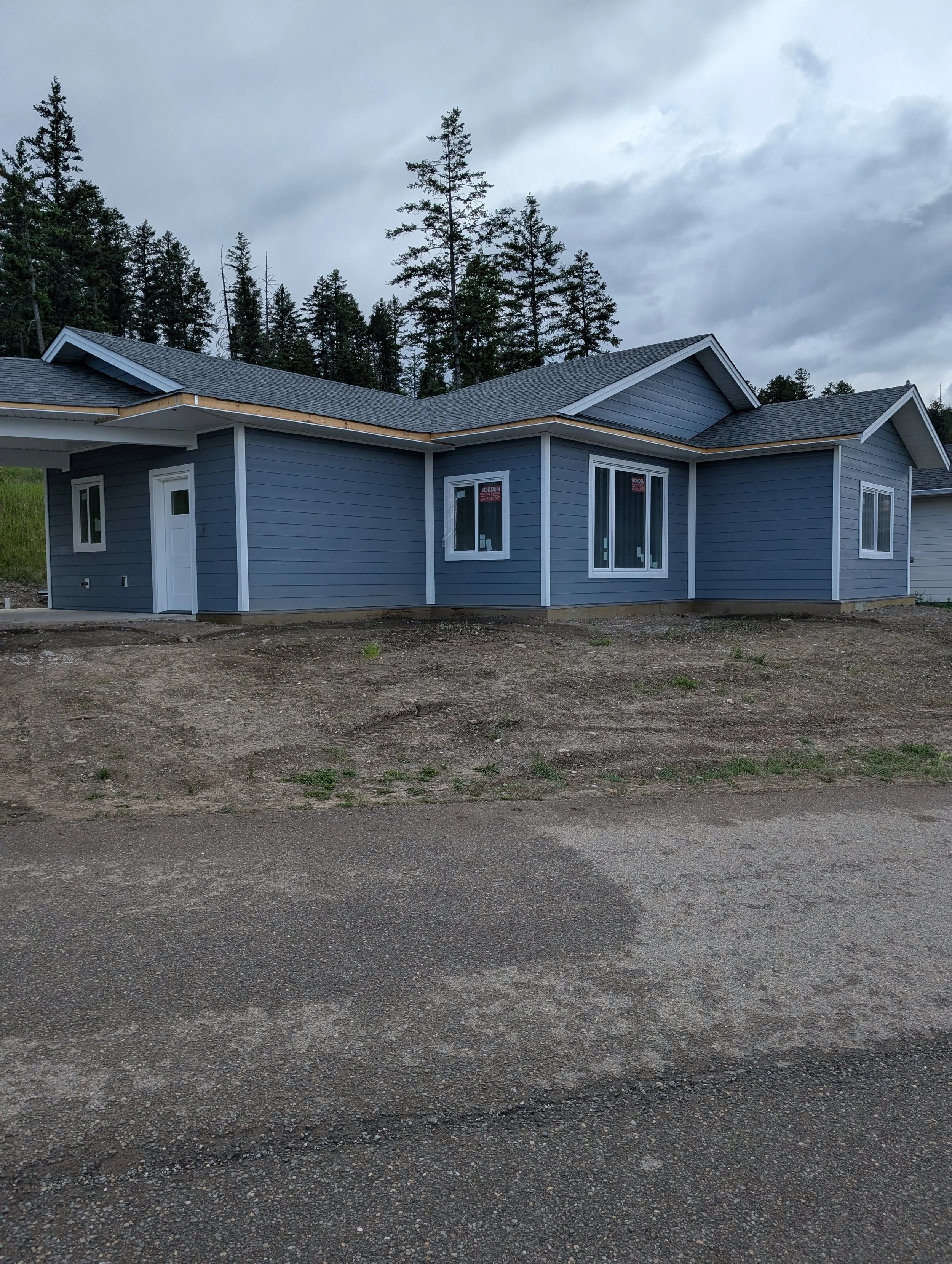 A house under construction with blue siding, multiple windows, and a dark shingled roof. Professional siding installation, replacement, and exterior renovations in Williams Lake and the Cariboo Region.