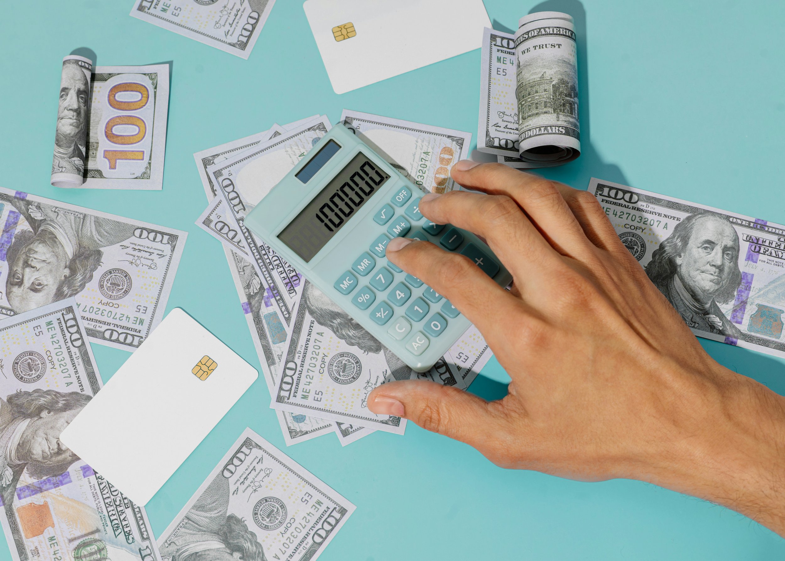 hand calculating value on calculator with money and credit cards to convey marketing and financial stability.
