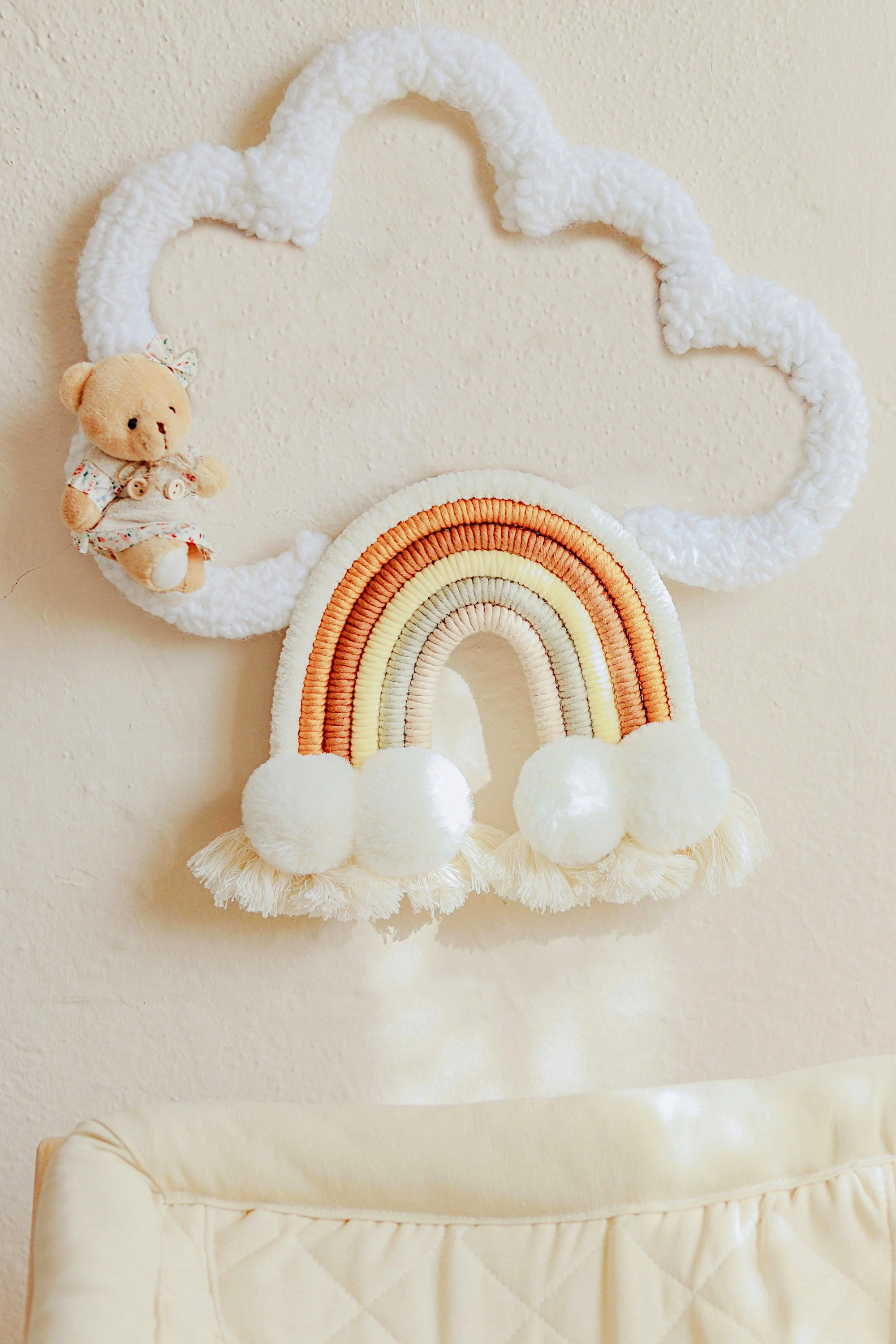 Baby Nursery Wall Decor With Rainbow and Clouds and a Small Plush Bear Toy.