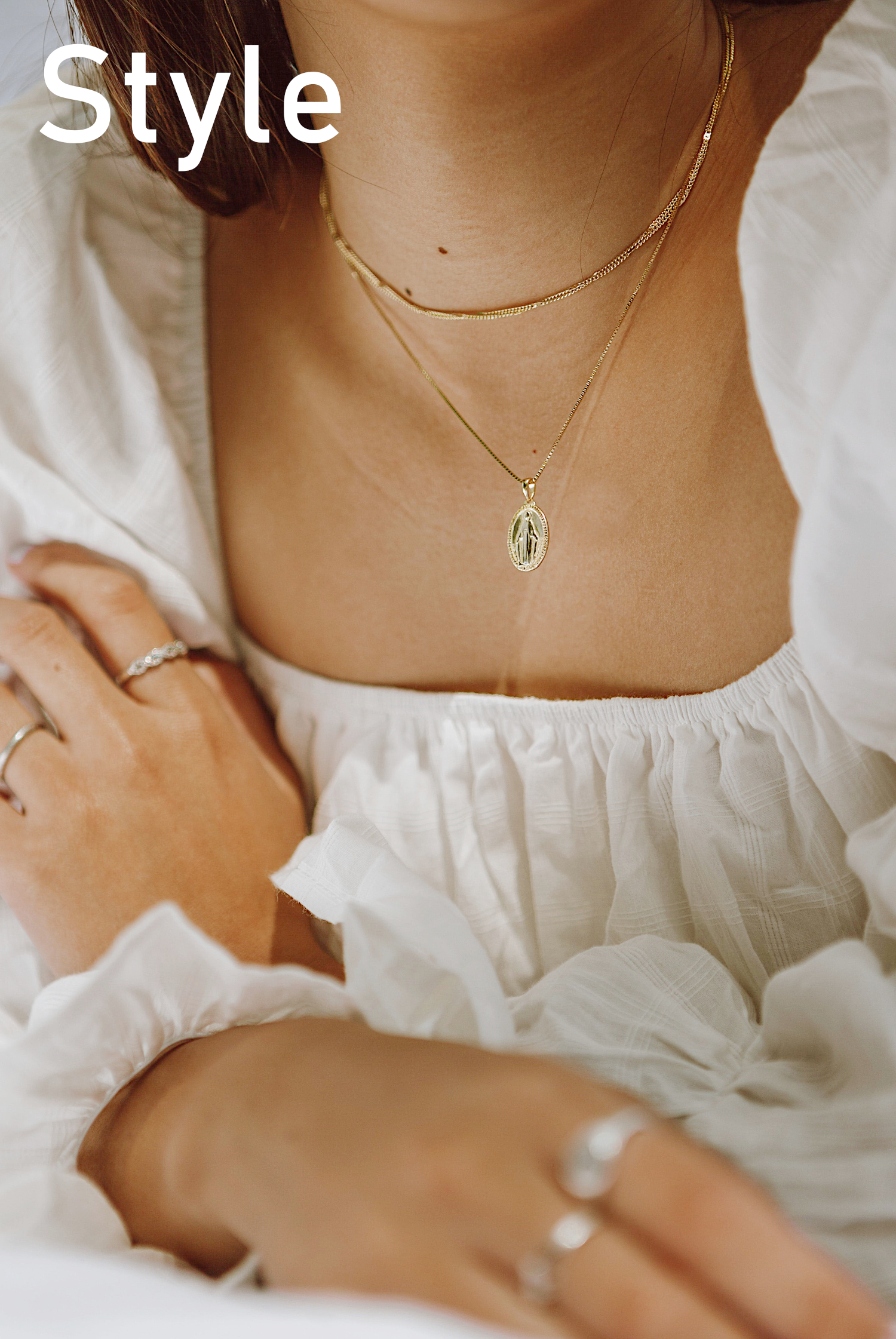 Close-Up of Woman's Neck and Hands Wearing White Dress, Necklaces and Rings. The Word Style Appears On the Top Left Corner of the Image.