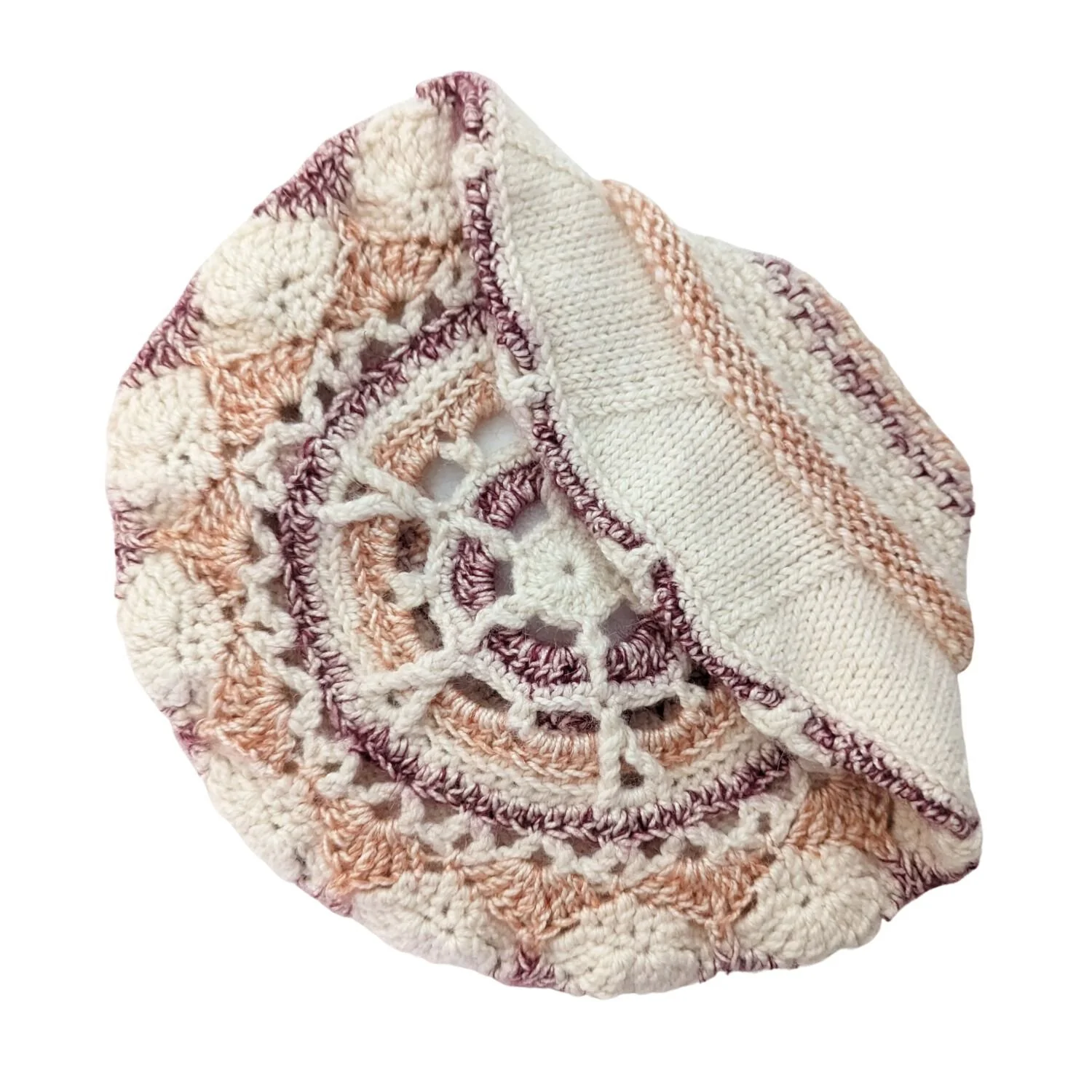 A close-up view of a multicolored crochet blanket with pink, white, and purple yarn, featuring different patterns, spread out on a white background.