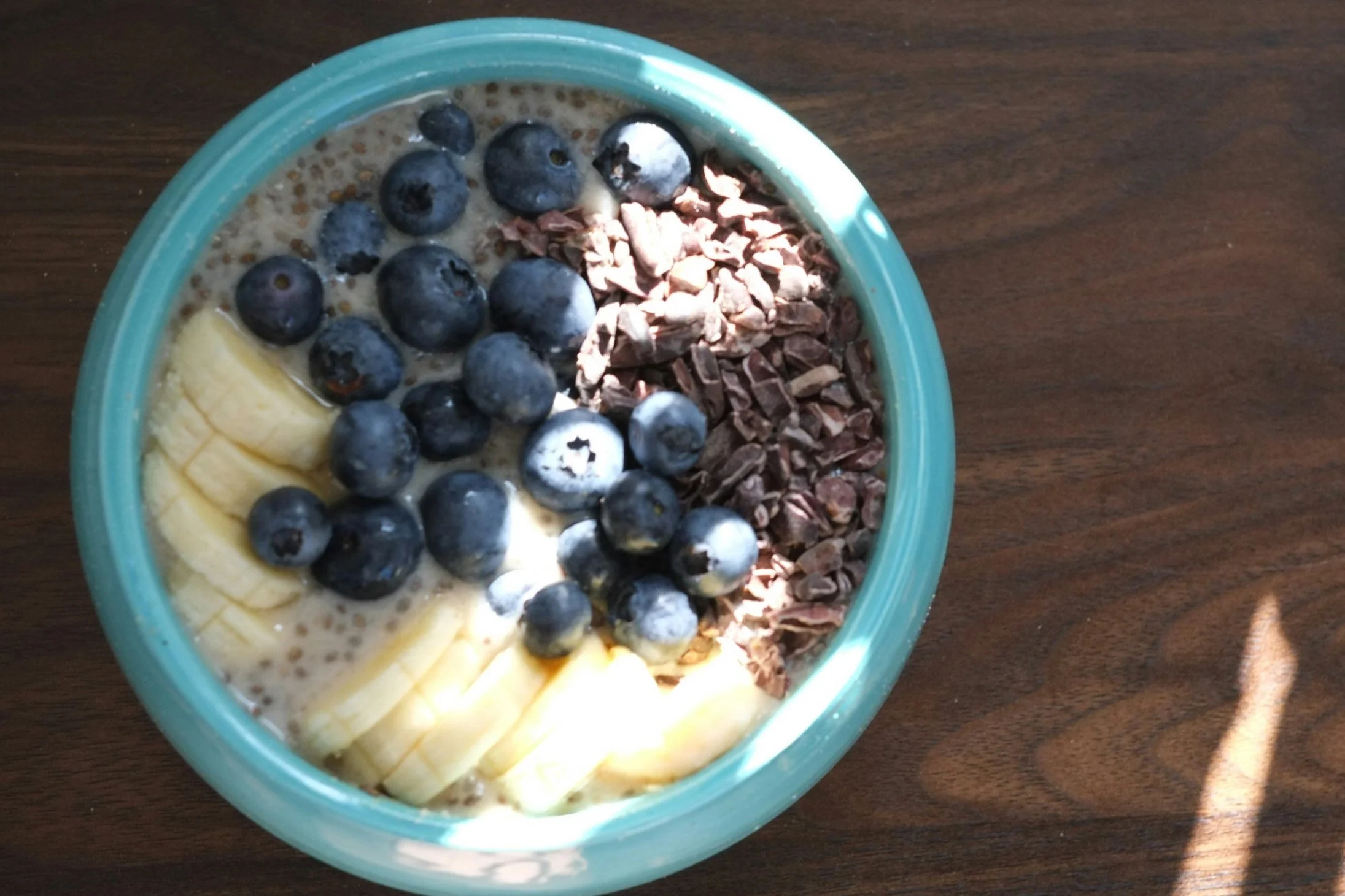 Bowl of oatmeal topped with blueberries, sliced bananas, and chopped chocolate.