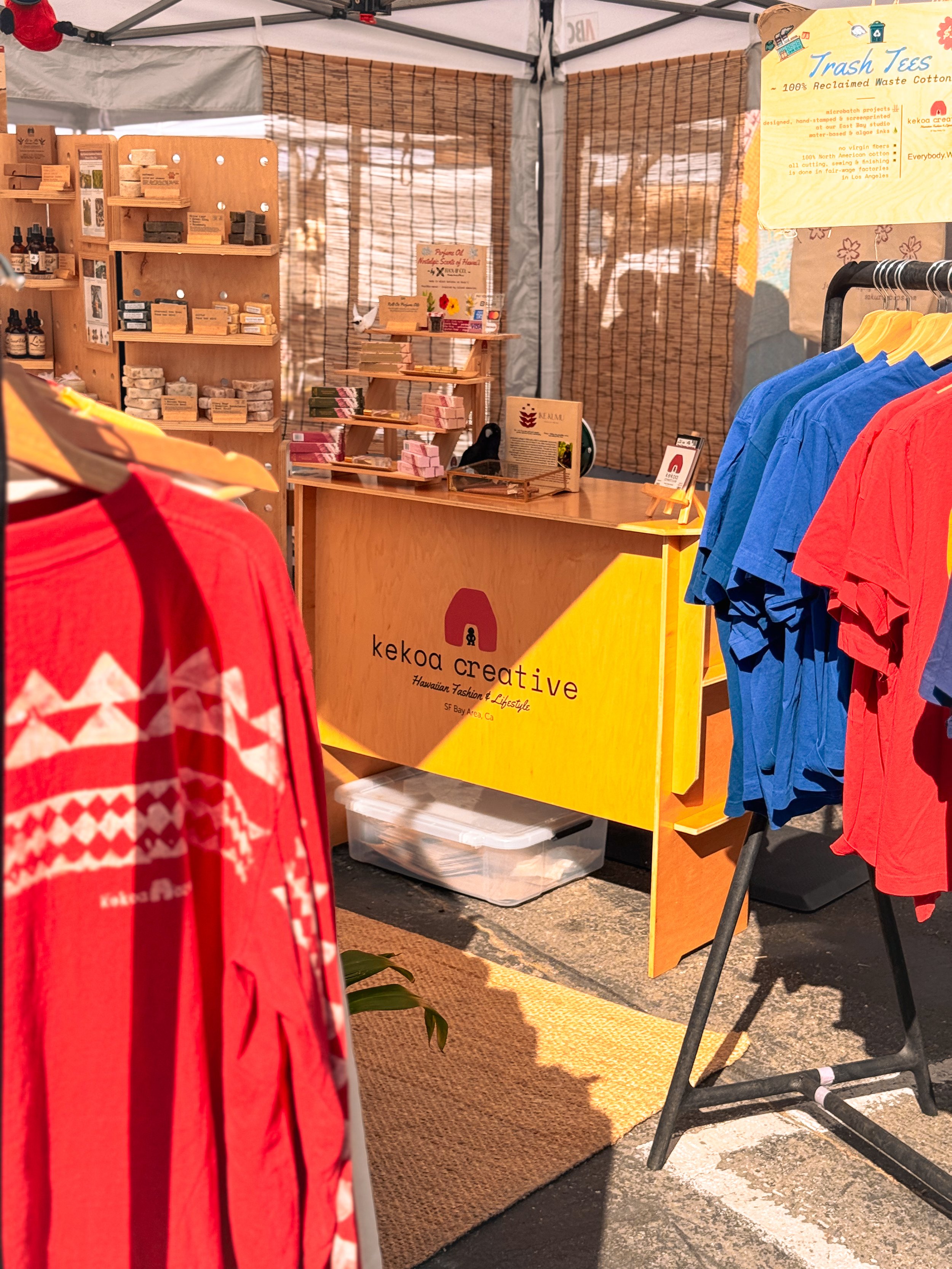 Kekoa Creative reclaimed waste cotton apparel and organic Hawaiian sandalwood skincare displayed inside marketplace booth.