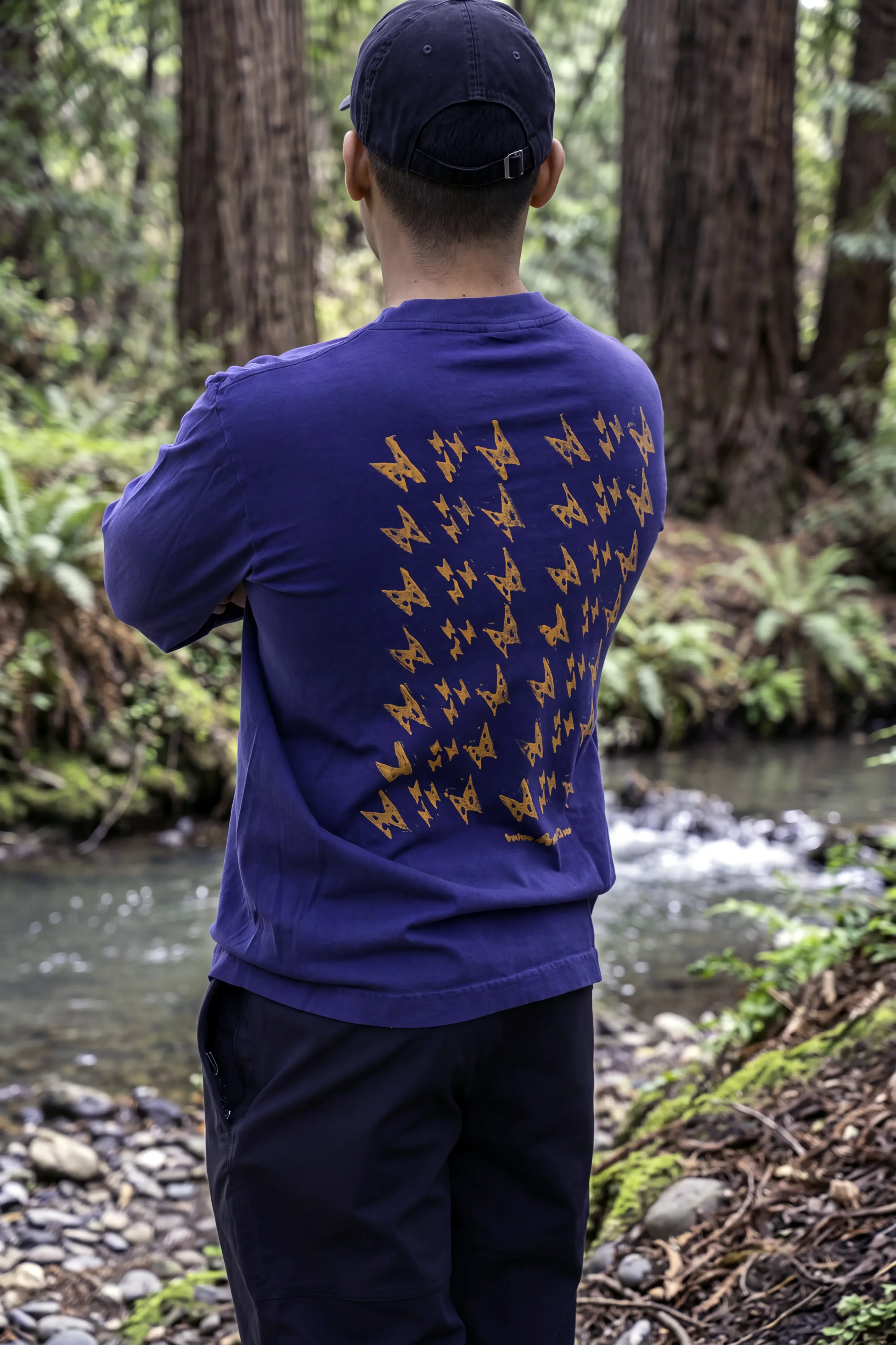 Back view of Kauila motif hand stamped in Lehua Mamo yellow Matsui Eco ink on dark navy long sleeve trash tee.