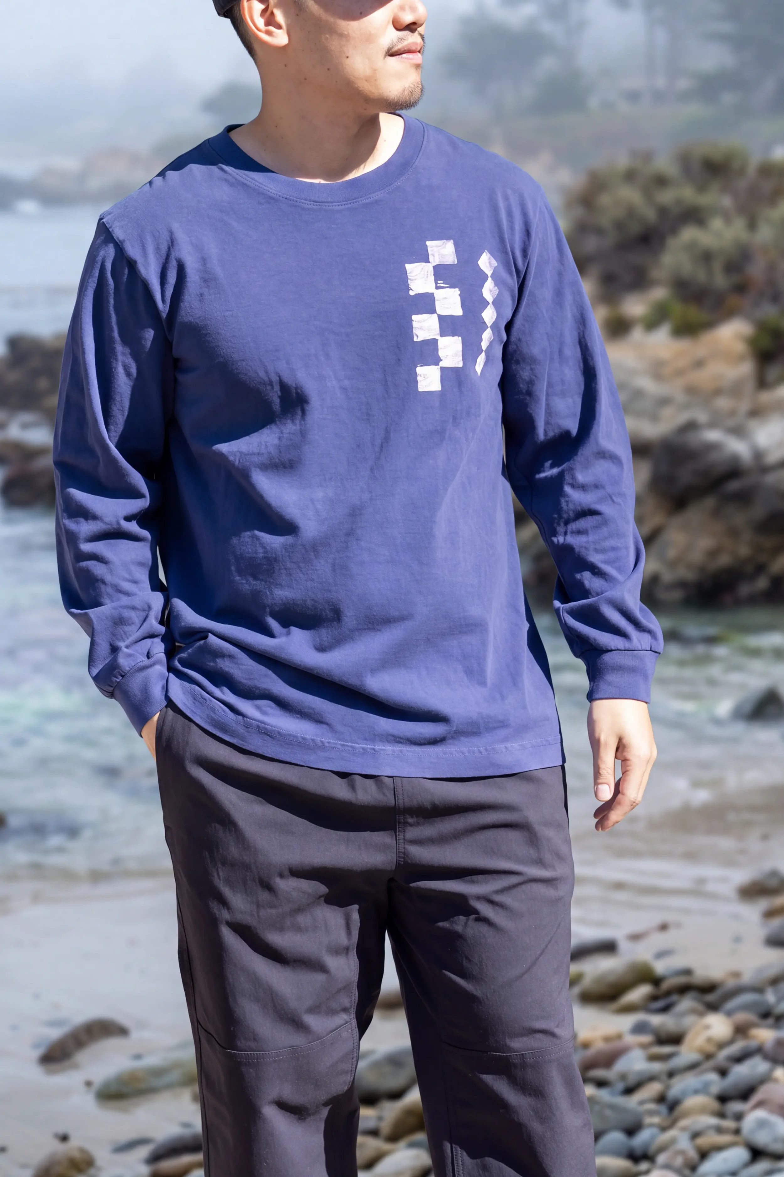 Model wearing unisex Dark Navy Kōnane long sleeve reclaimed cotton trash tee with front chest discharge print by Kekoa Creative.