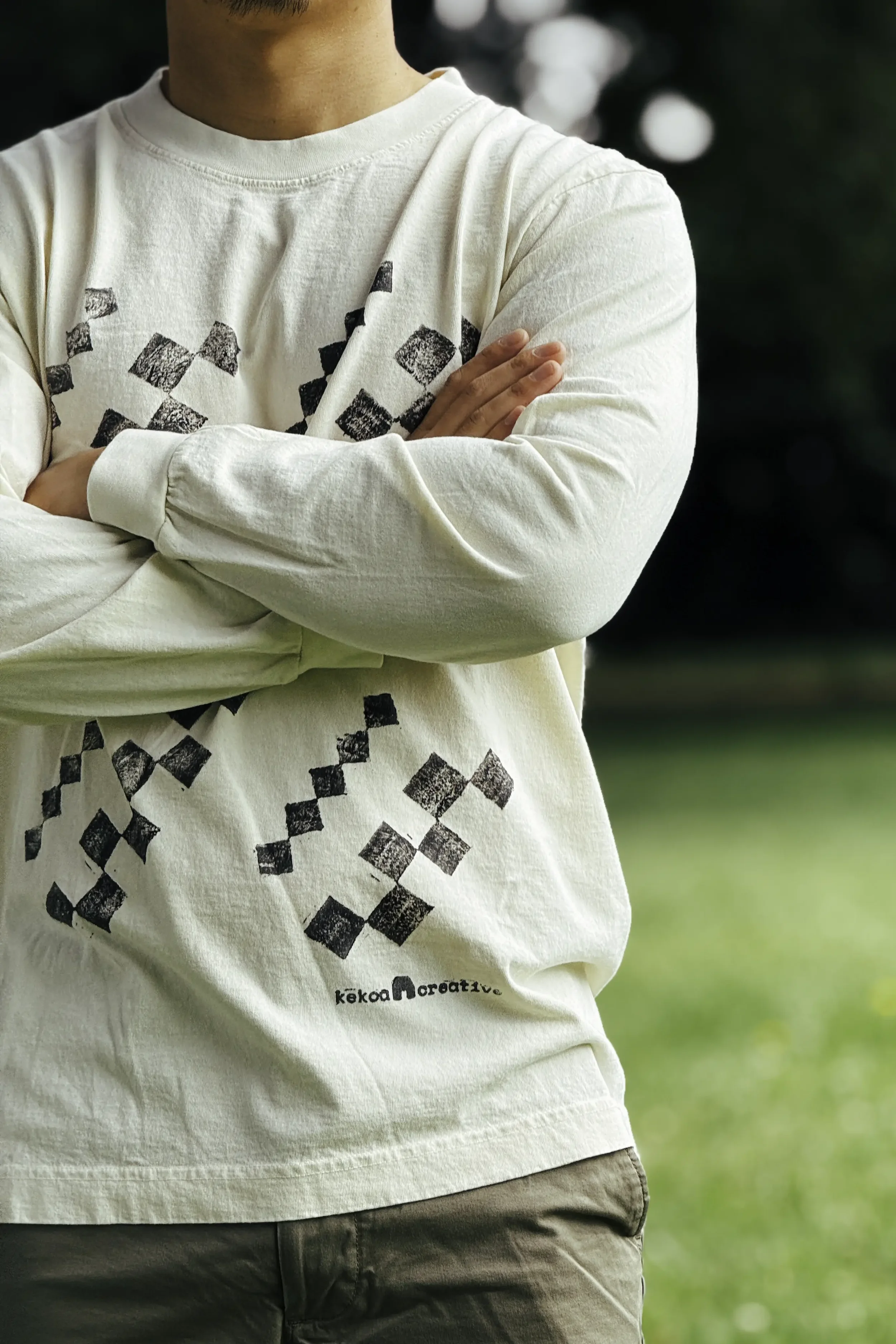 Model wearing unisex natural undyed Kōnane long sleeve reclaimed cotton trash tee with front algae ink kapala print by Kekoa Creative.