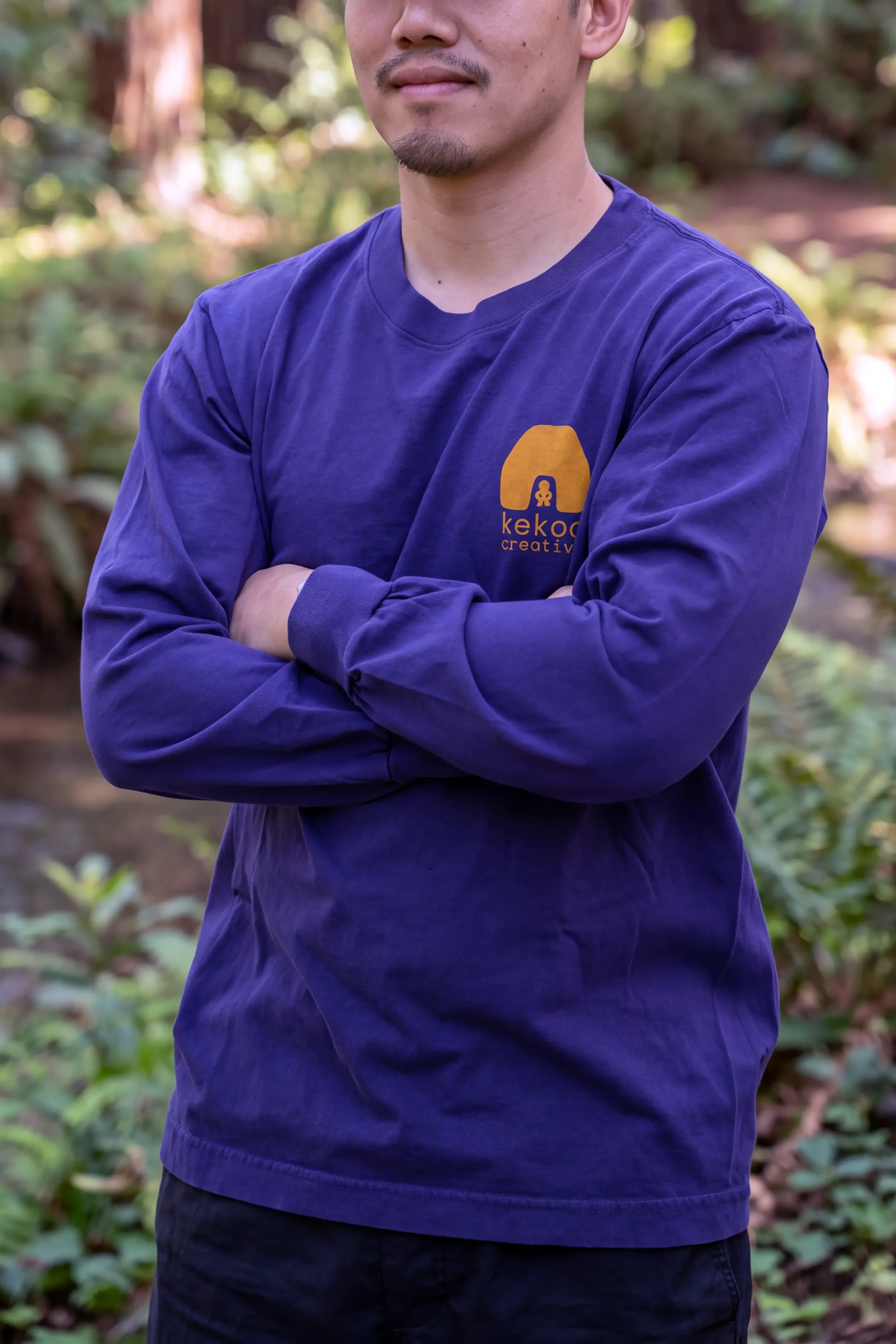 Model wearing unisex Dark Navy Blue Kauila long sleeve reclaimed cotton trash tee with yellow chest logo by Kekoa Creative.