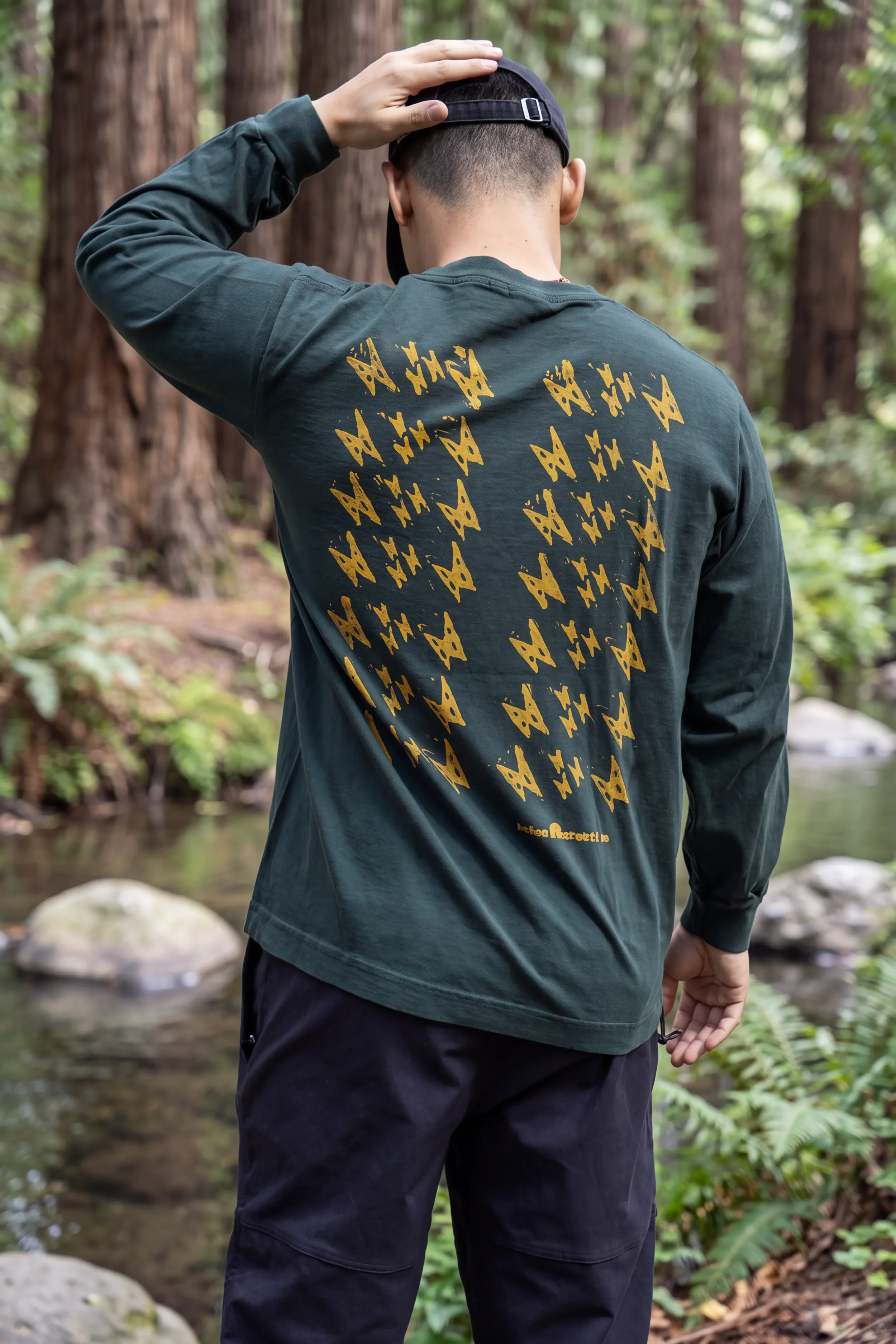 Back detail of Kauila motif hand stamped in Lehua Mamo yellow ink on green long sleeve trash tee.