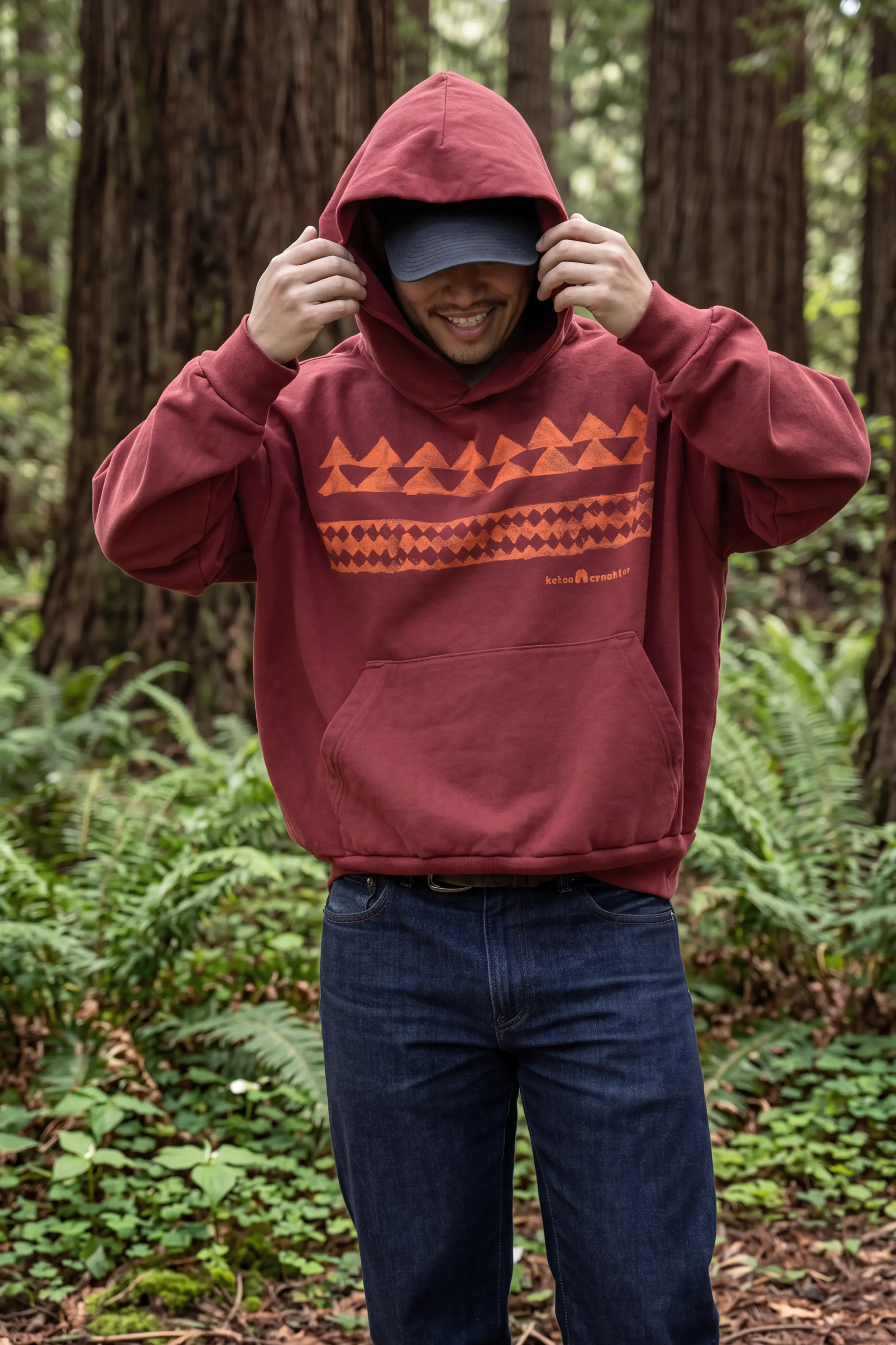 Model wearing unisex ʻŌhelo Red He Mano Ka Niho drop-shoulder boxy trash hoodie in 100% reclaimed waste cotton by Kekoa Creative.