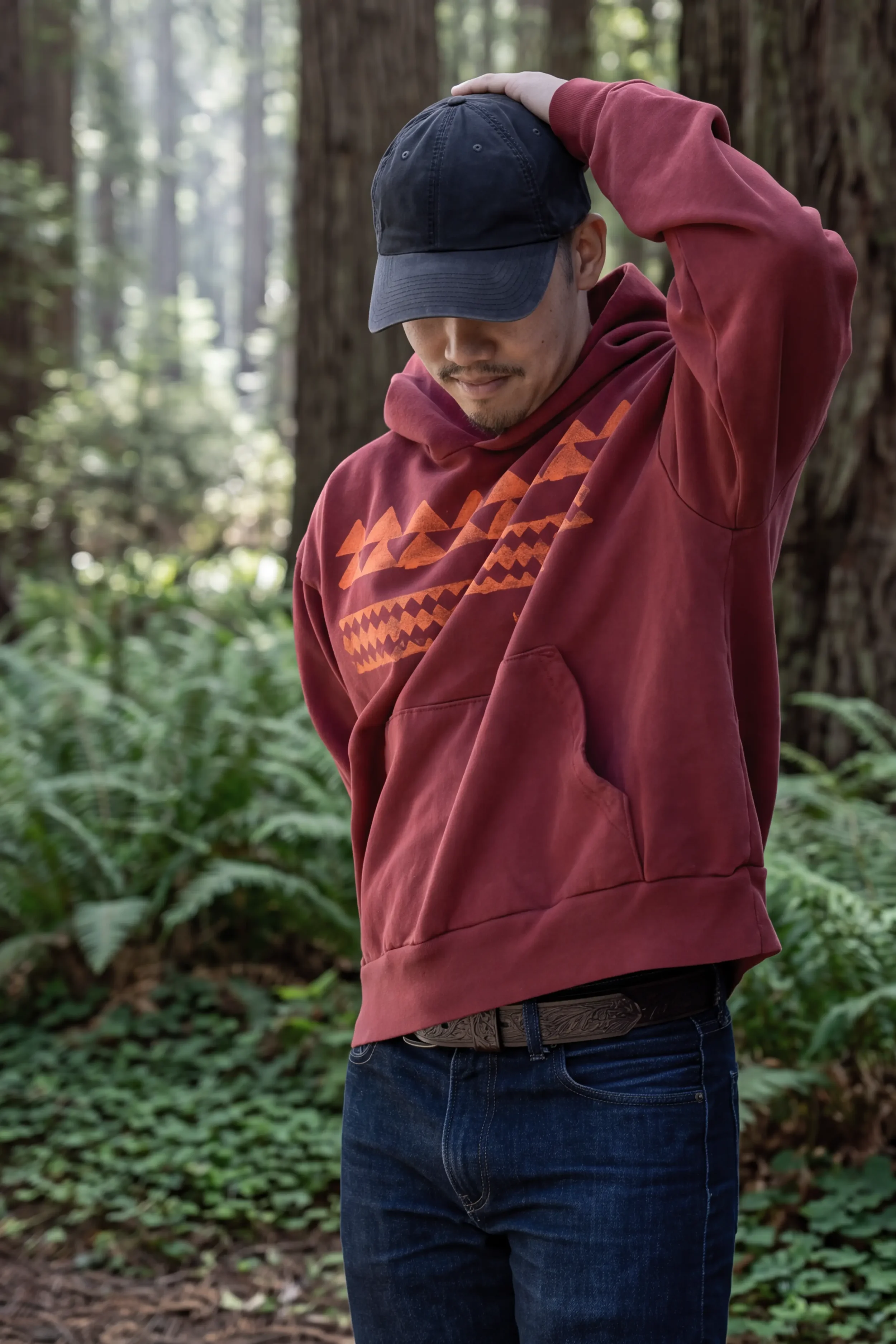 Model wearing unisex ʻŌhelo Red He Mano Ka Niho drop-shoulder boxy trash hoodie in 100% reclaimed waste cotton by Kekoa Creative.