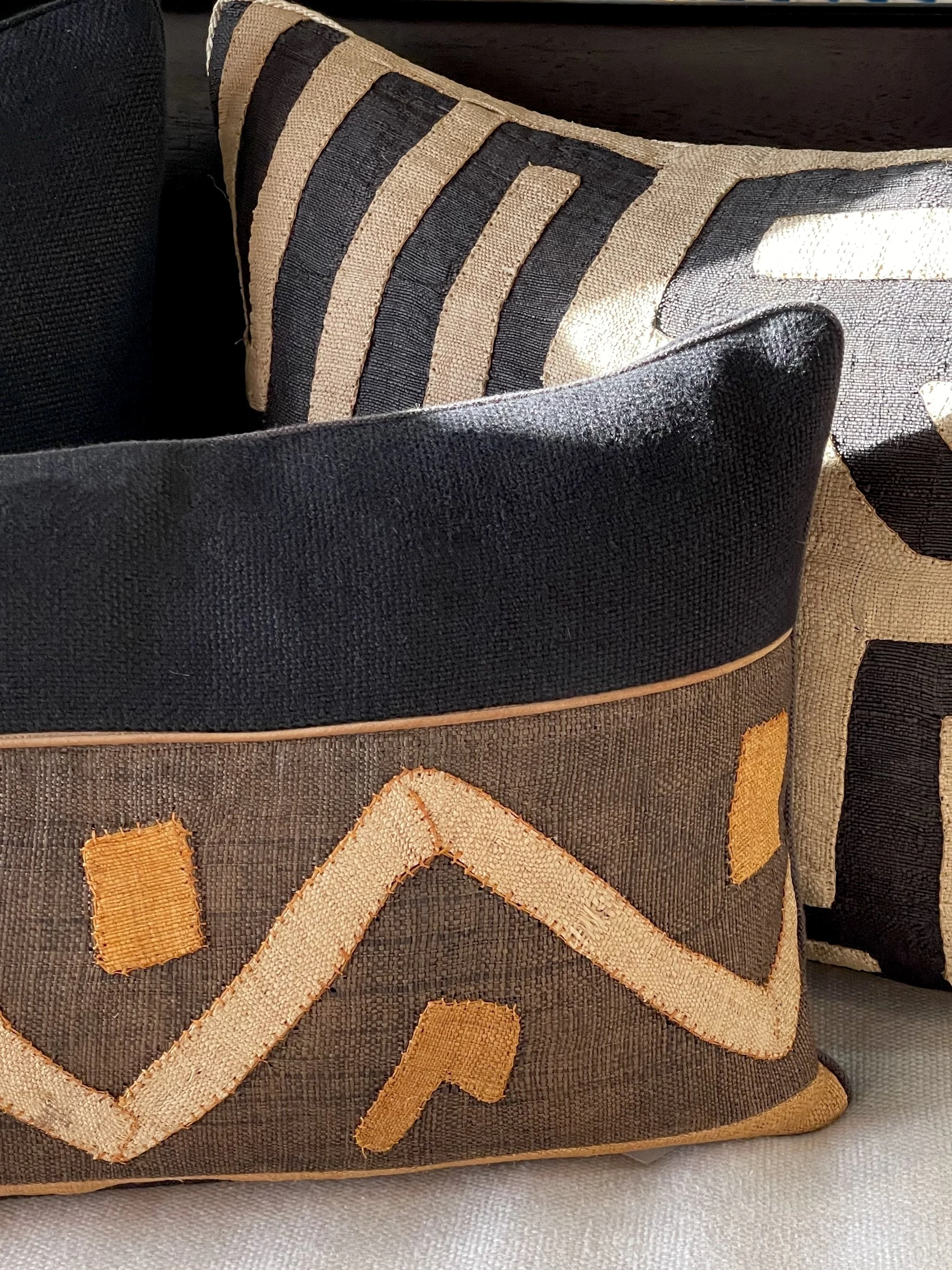 Close-up of a fabric bag with black, beige, and yellow embroidered geometric patterns.