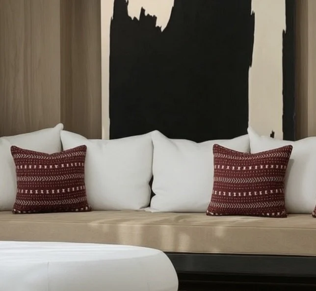 White sofa with red patterned throw pillows, wooden wall paneling, and an abstract black and white artwork in the background.